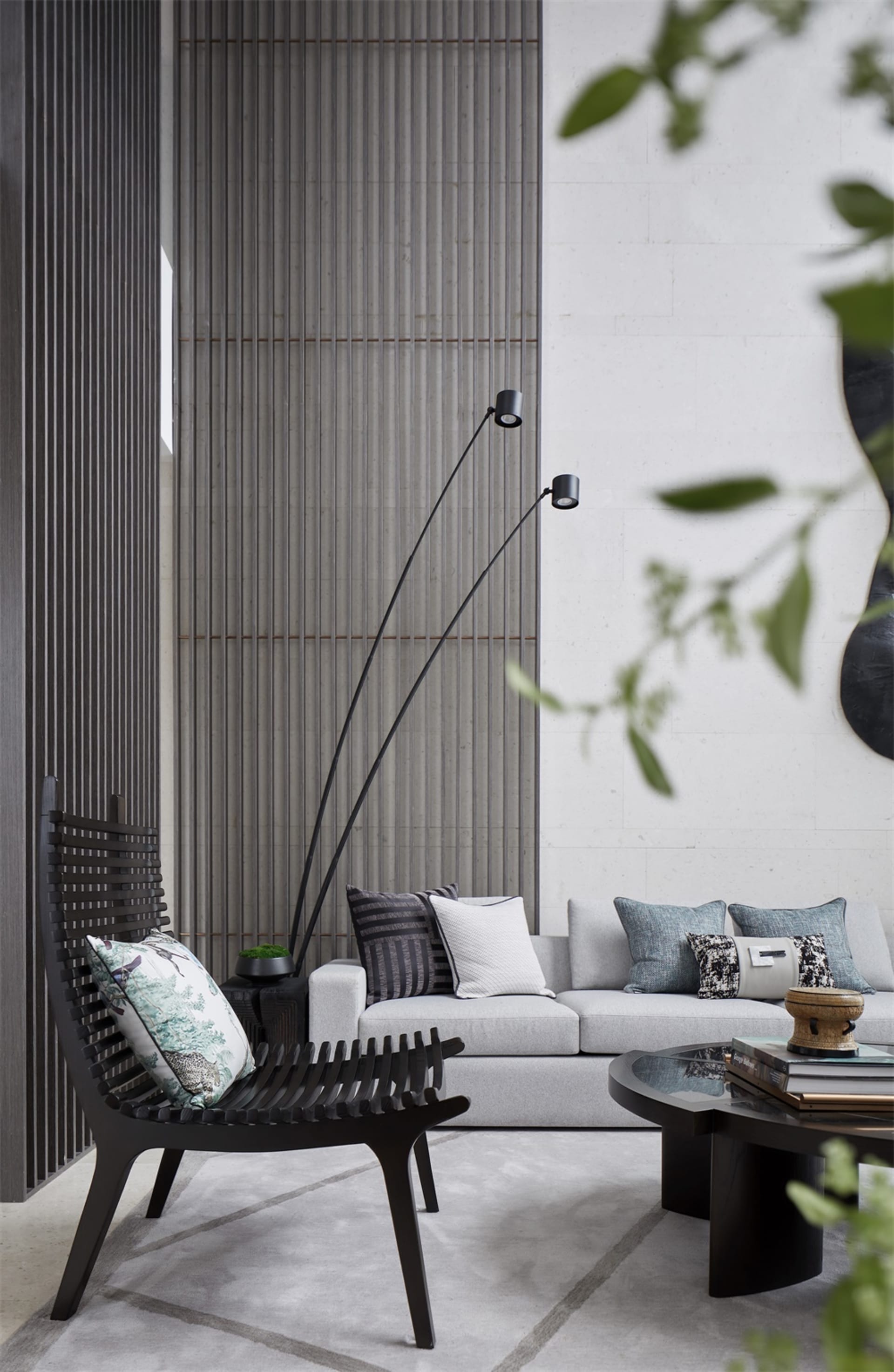 Modern minimalist living room featuring a sleek concrete wall, grey sofa, and black armchair