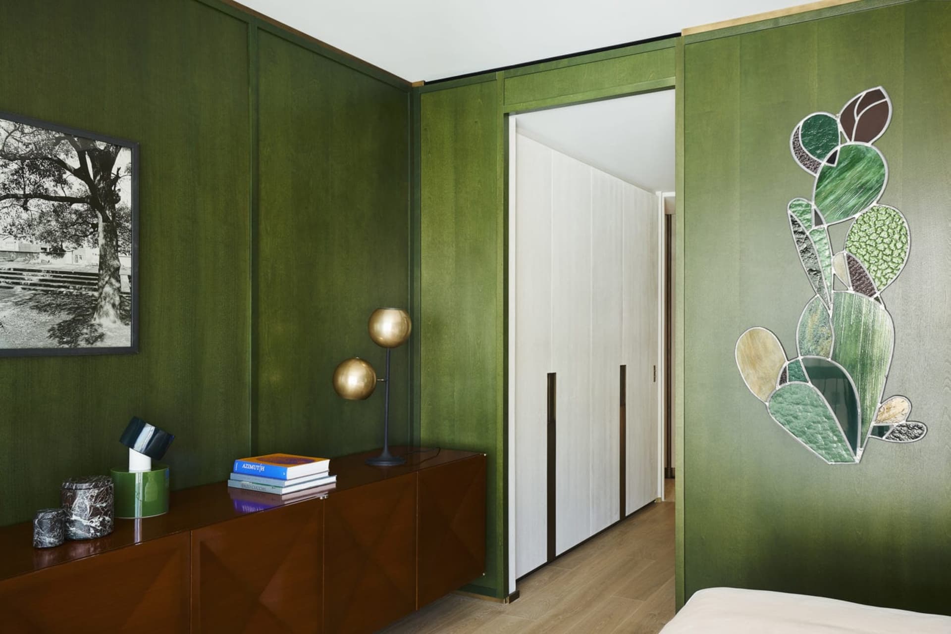 A modern bedroom with green textured walls, wooden floors, and a white bed.