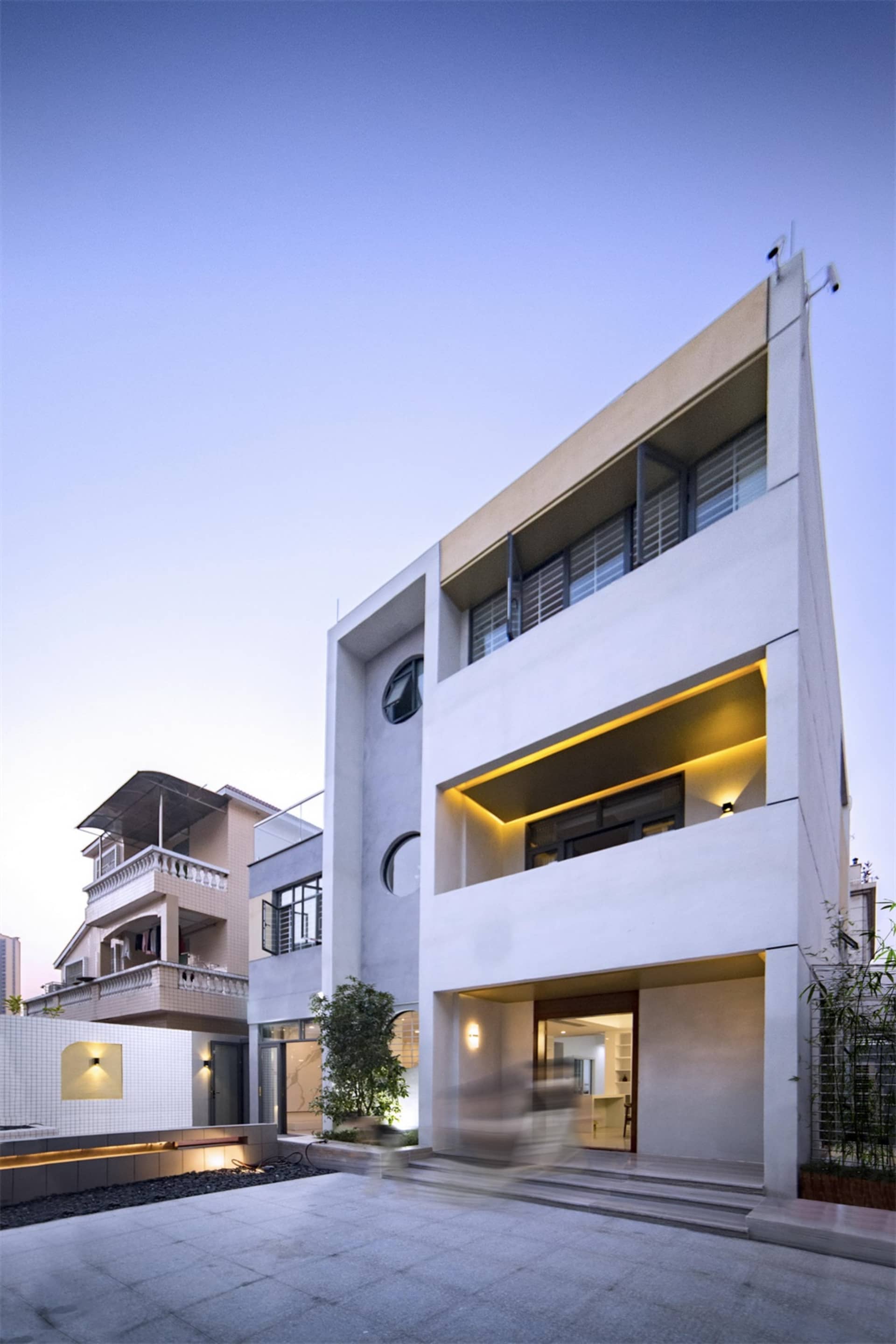 Modern minimalist white residential interior with concrete elements and large windows.