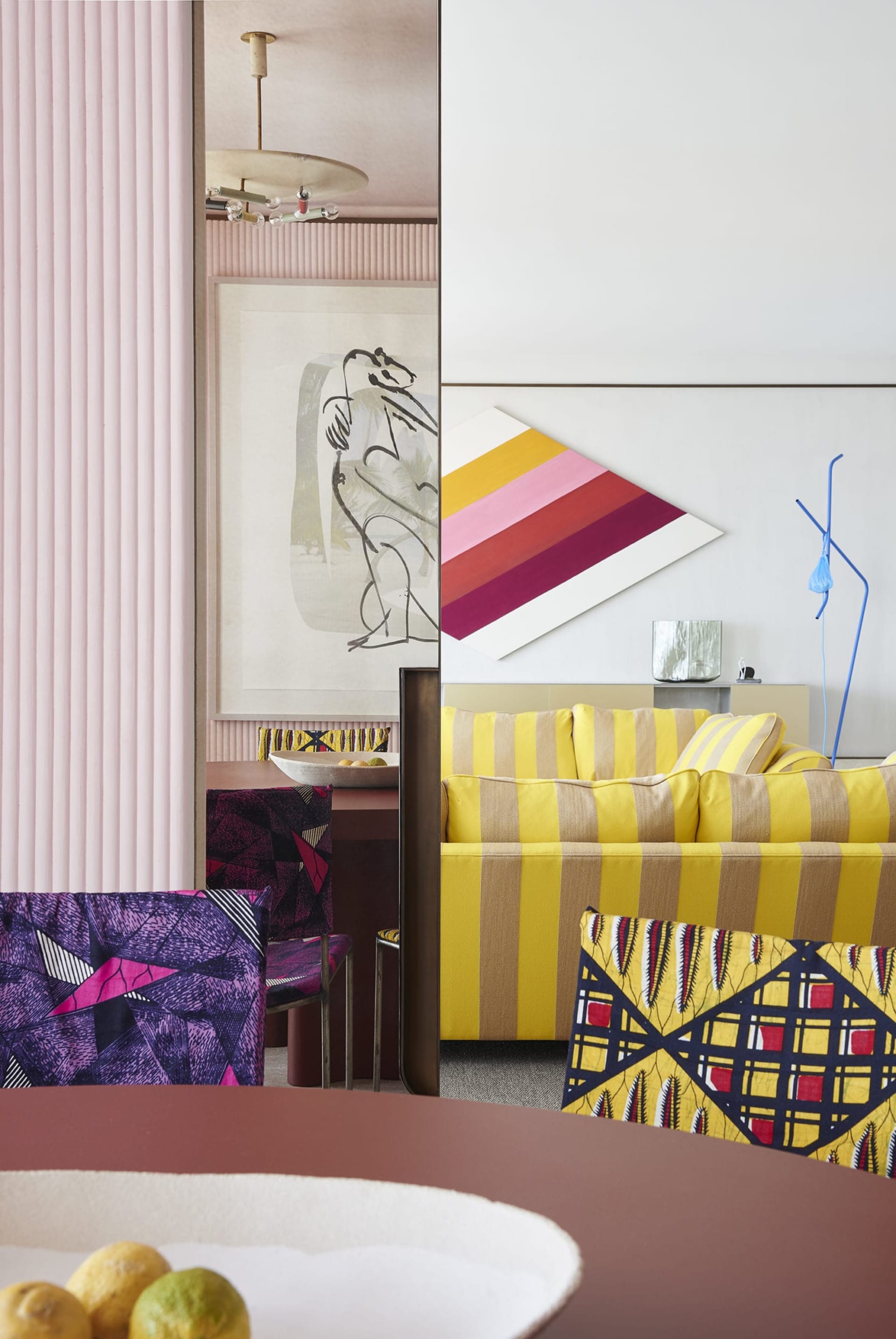 A modern living room featuring vibrant yellow striped sofas and colorful chairs.