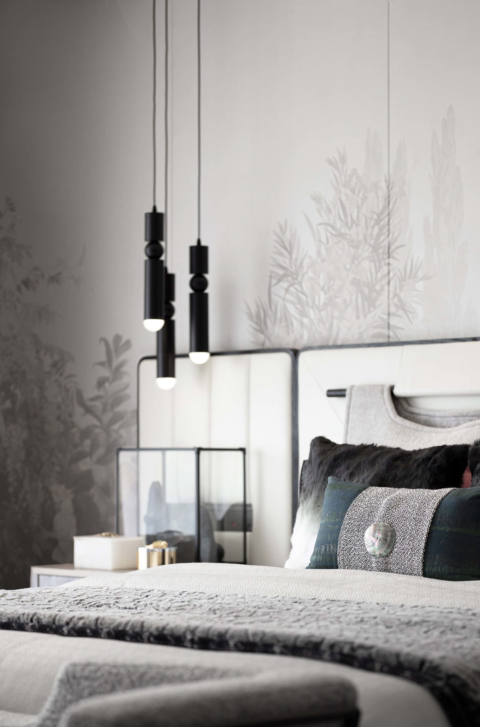 Modern minimalist bedroom featuring textured fabric bedding, wooden headboard, and metal pendant lights with botanical print