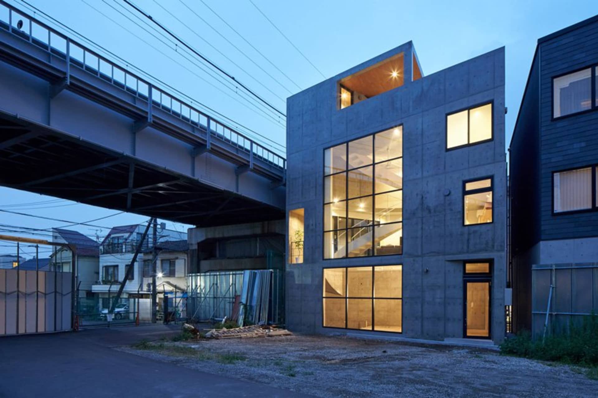 Contemporary house with concrete walls and large glass windows at dusk.