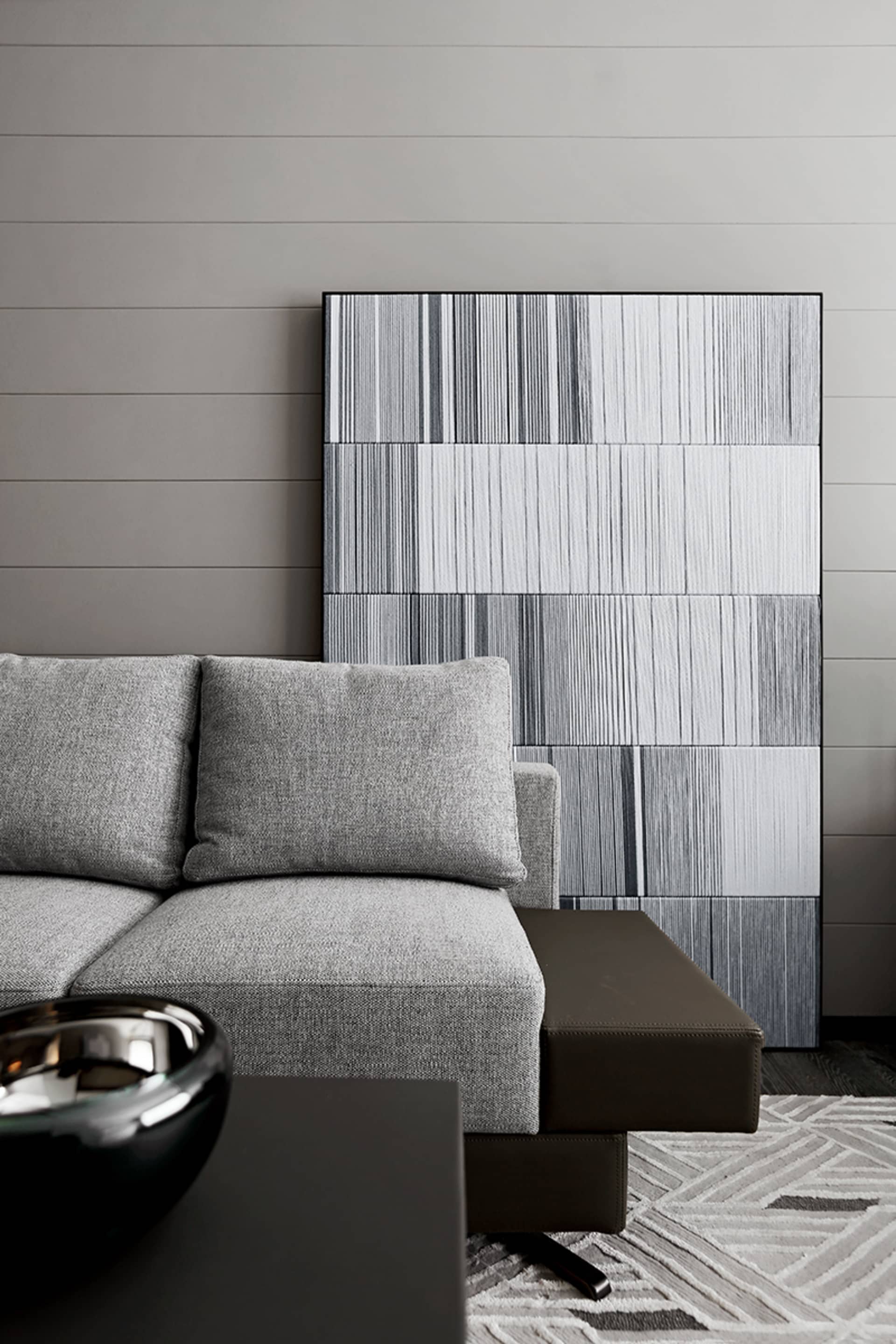 Modern grey sofa in a contemporary living room with abstract wall art and a geometric rug.