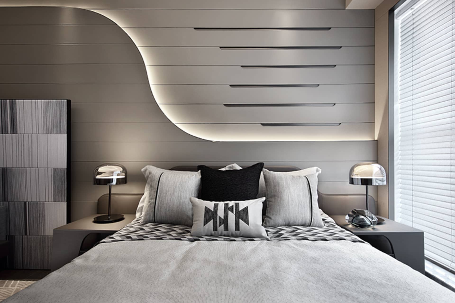 A modern bedroom featuring a large platform bed with metal frame and wood headboard, complemented by a sleek geometric headbo