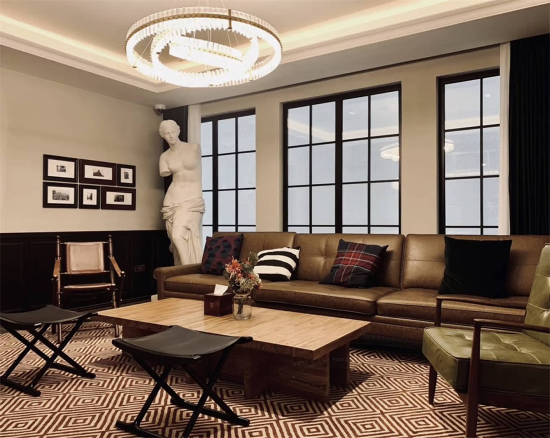A living room with a leather sofa and wooden coffee table, featuring industrial design elements such as exposed metal beams a