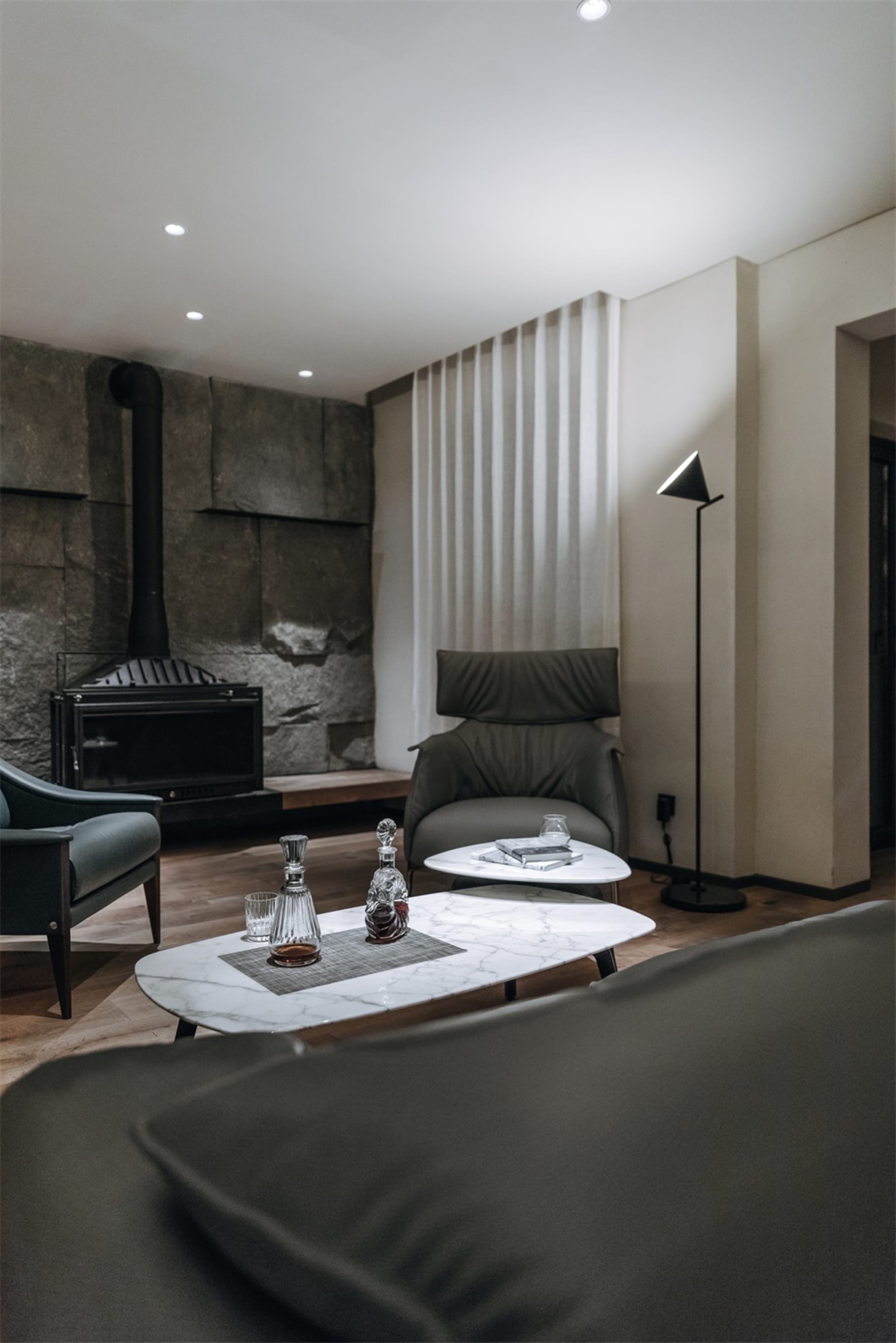 Modern minimalist living room featuring marble coffee tables and a leather armchair, providing a comfortable and sophisticate