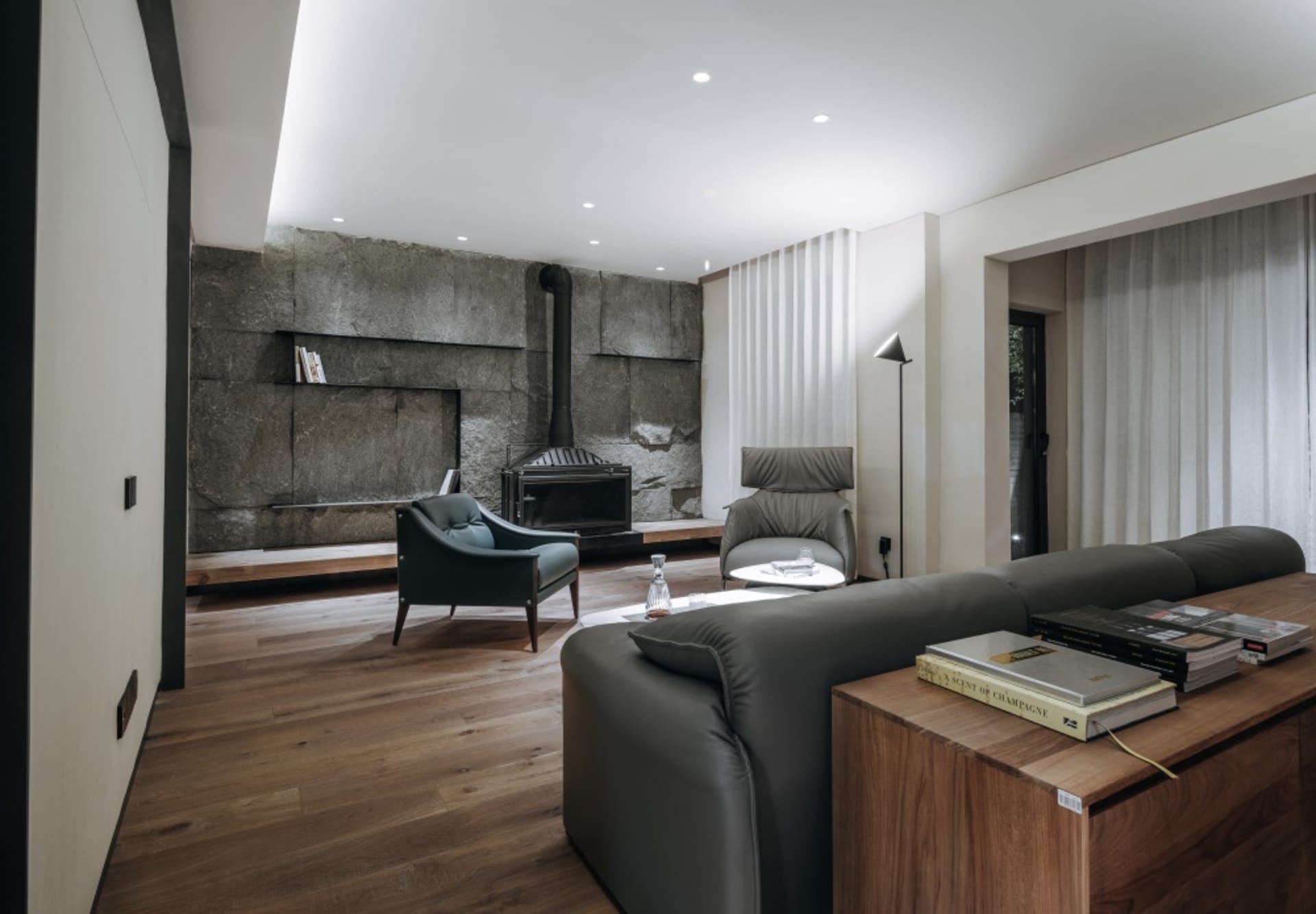 Modern living room featuring a textured concrete wall, natural wood floor, and minimalist furniture.