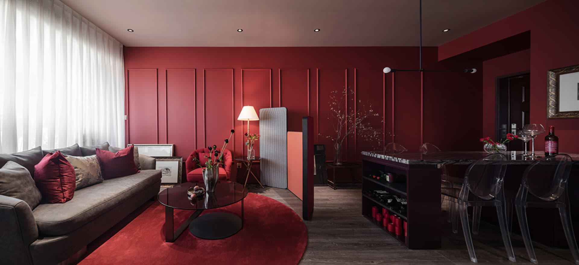 A modern residential interior featuring a living room with a red accent wall, marble coffee table, glass side table, and meta