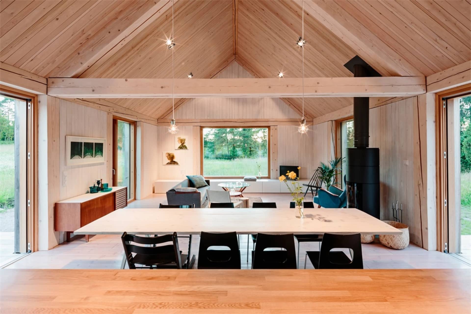 A minimalist living room with wooden furniture and a high ceiling.