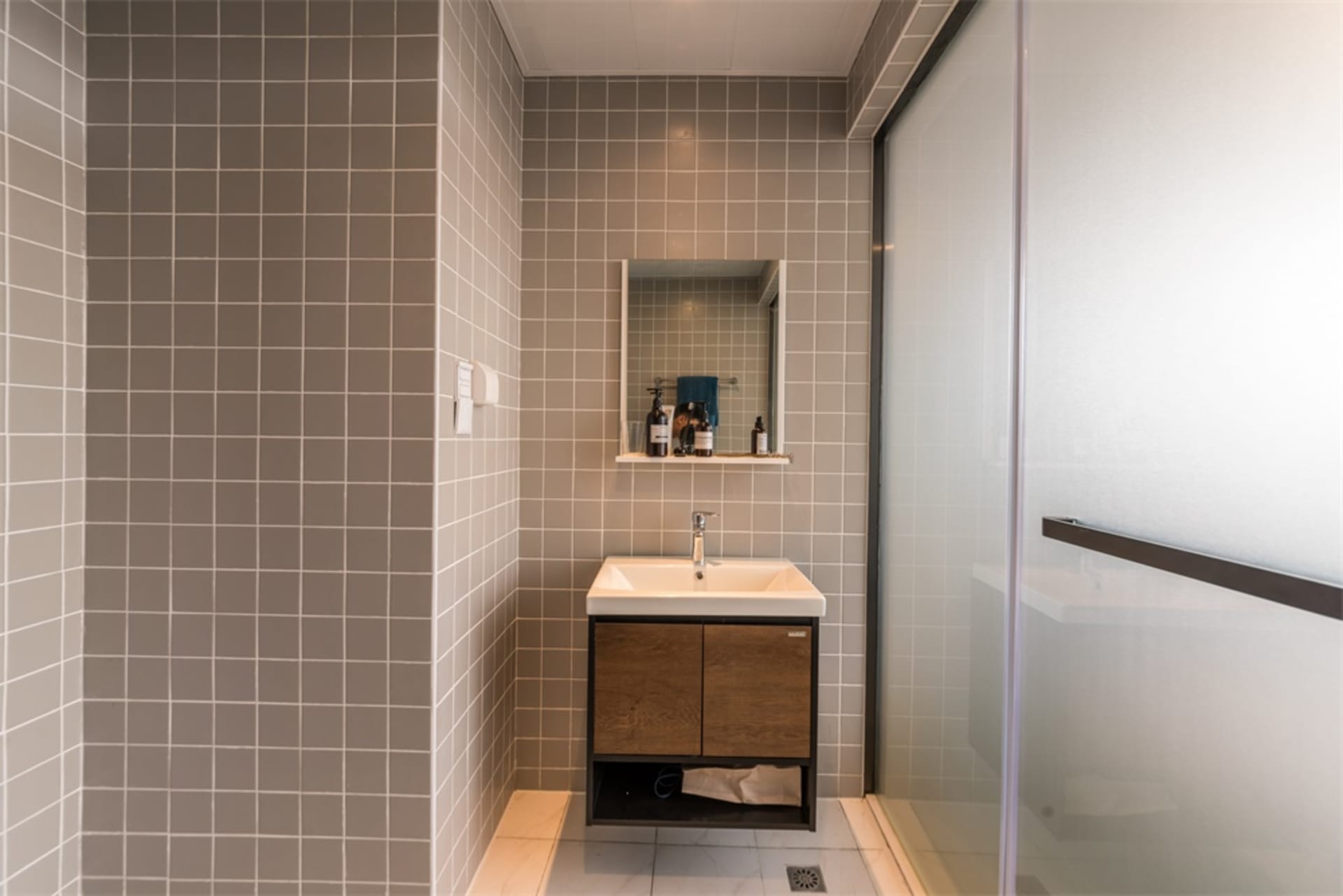 Modern bathroom with gray tile walls, a sink, and a mirror.