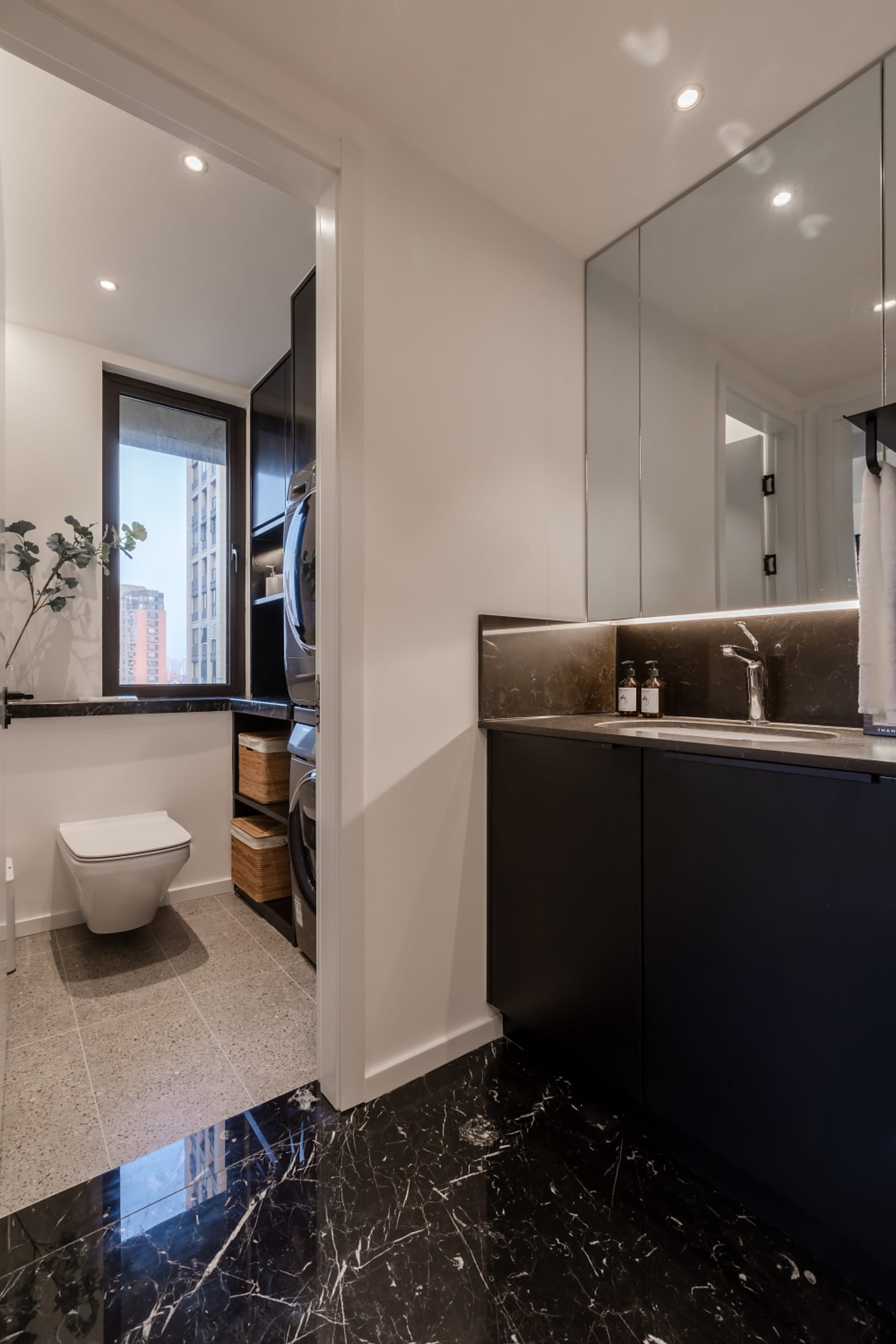 A modern bathroom and laundry room with marble flooring and minimalist design.
