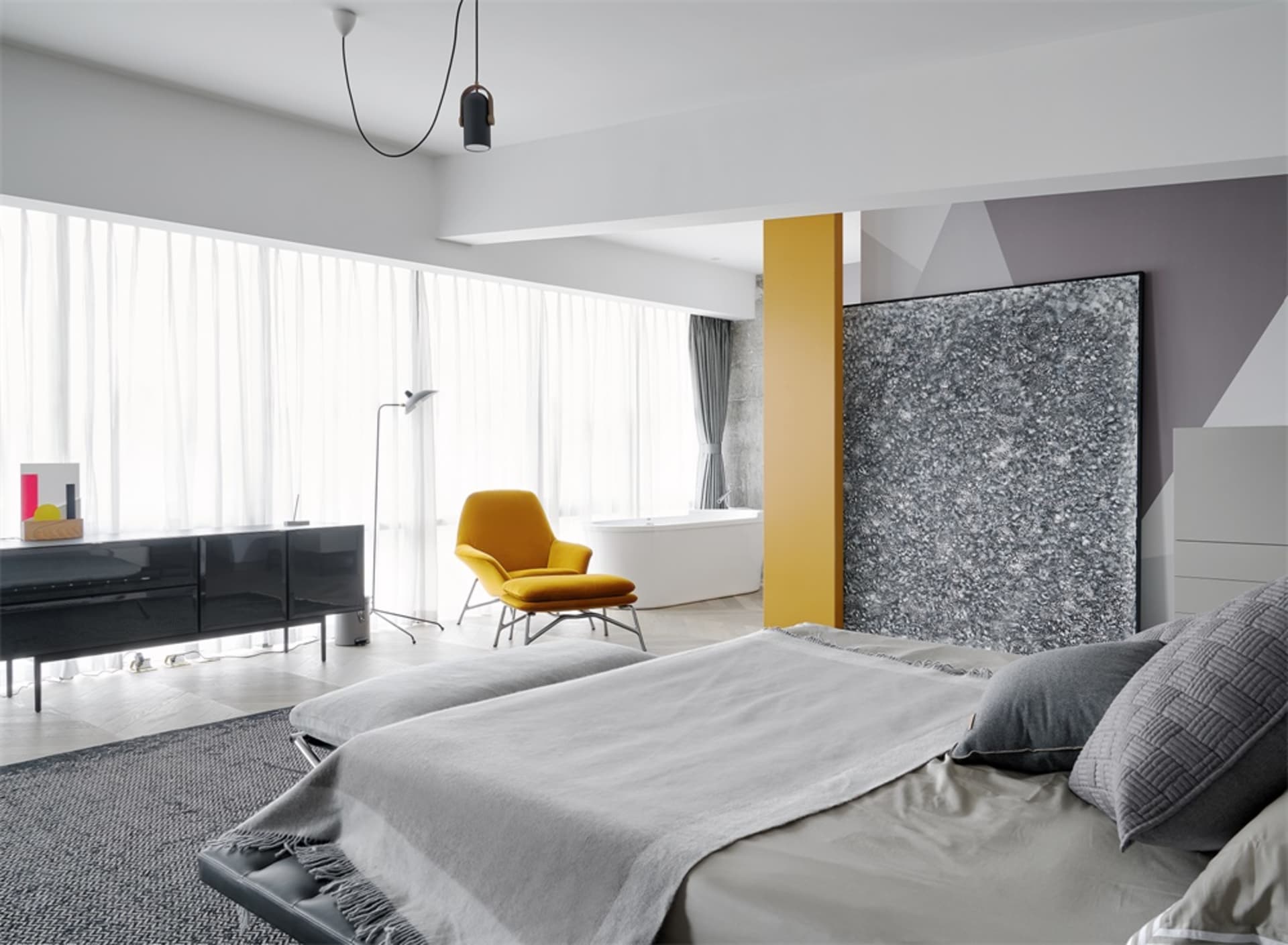 A modern minimalist bedroom featuring a bed with a gray blanket, leather headboard, and a yellow chair.
