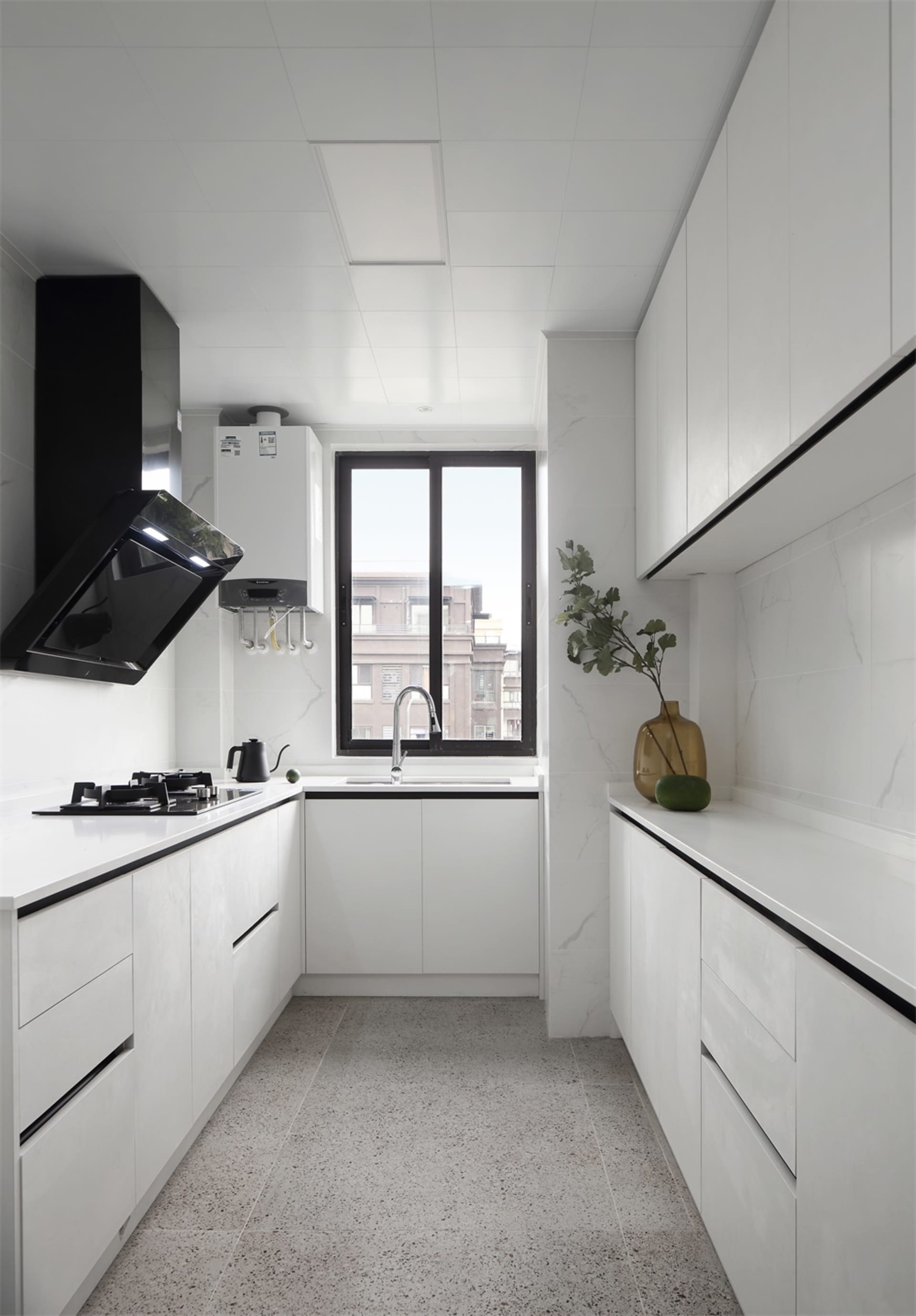 A contemporary kitchen with sleek white marble countertops and cabinets, featuring a sink, stove, and minimalist design eleme