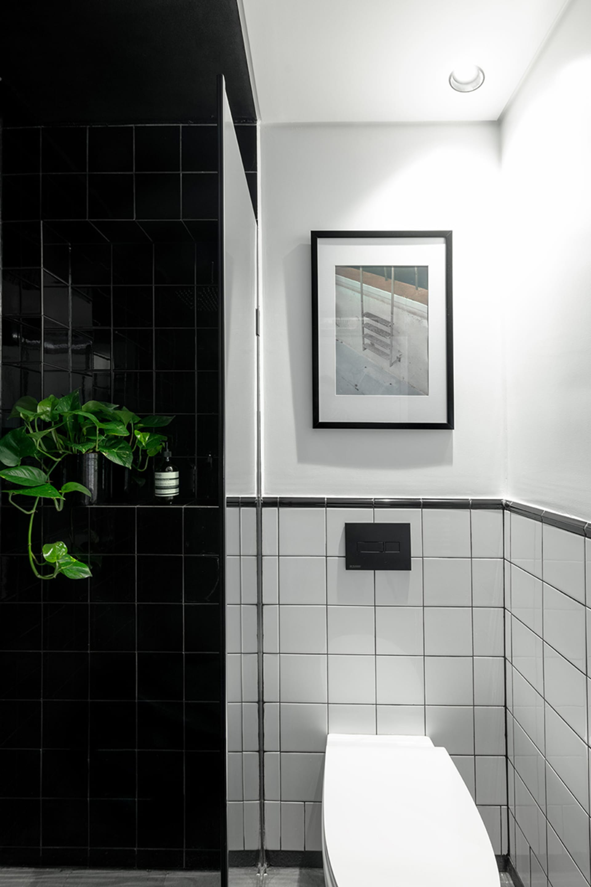 Minimalist black and white bathroom with a white toilet and black tiled walls.