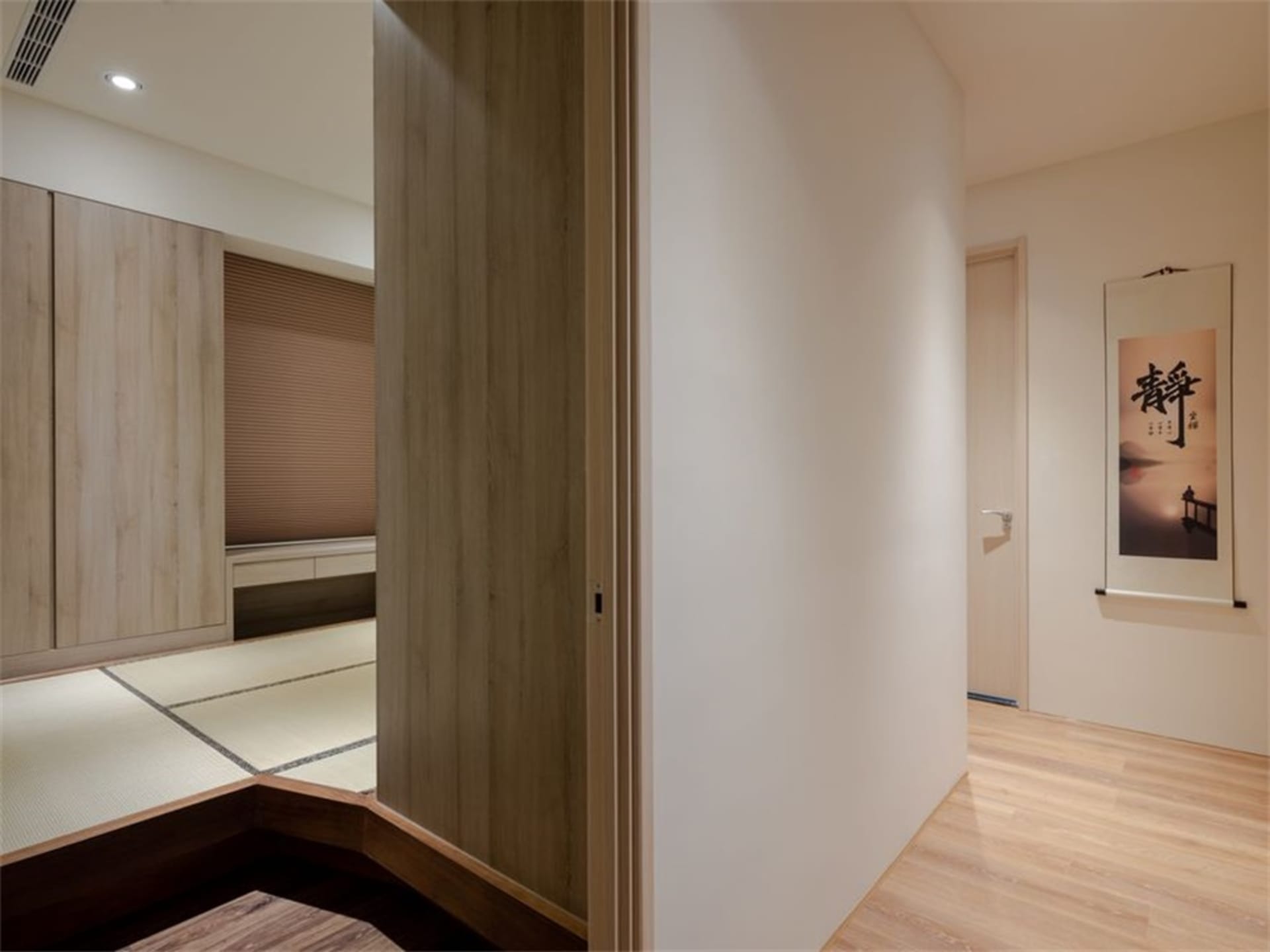 A minimalist-style room featuring a Japanese tatami mat floor and light-colored wooden furniture and walls.