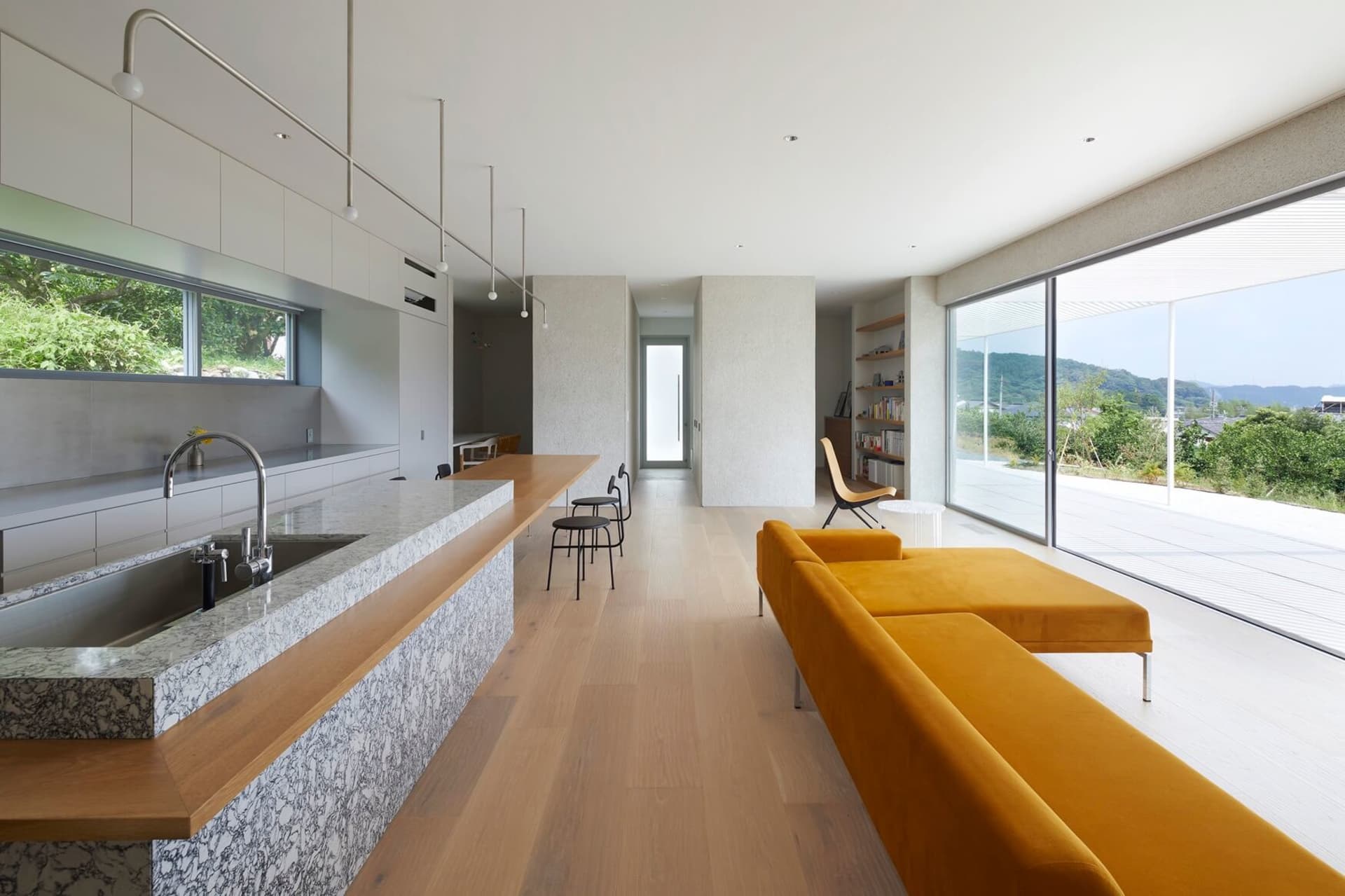 A contemporary residential living room featuring marble countertops, wooden flooring, and glass elements.