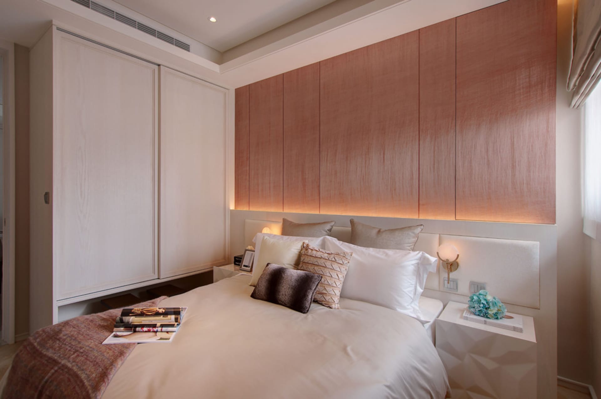 A minimalist bedroom featuring a white bed with a wooden headboard and white furniture.