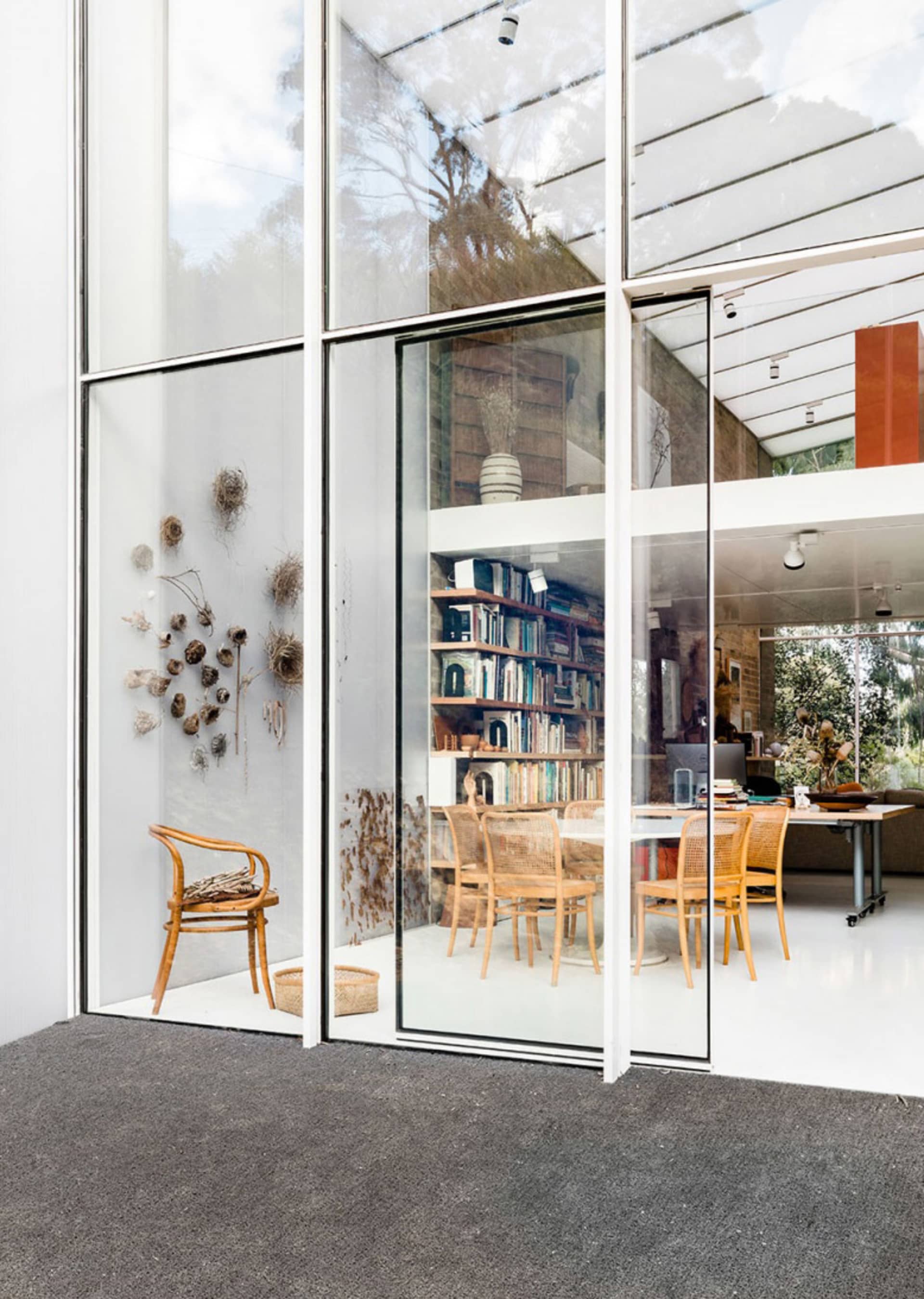 Modern interior living room with floor-to-ceiling glass walls and a library area.