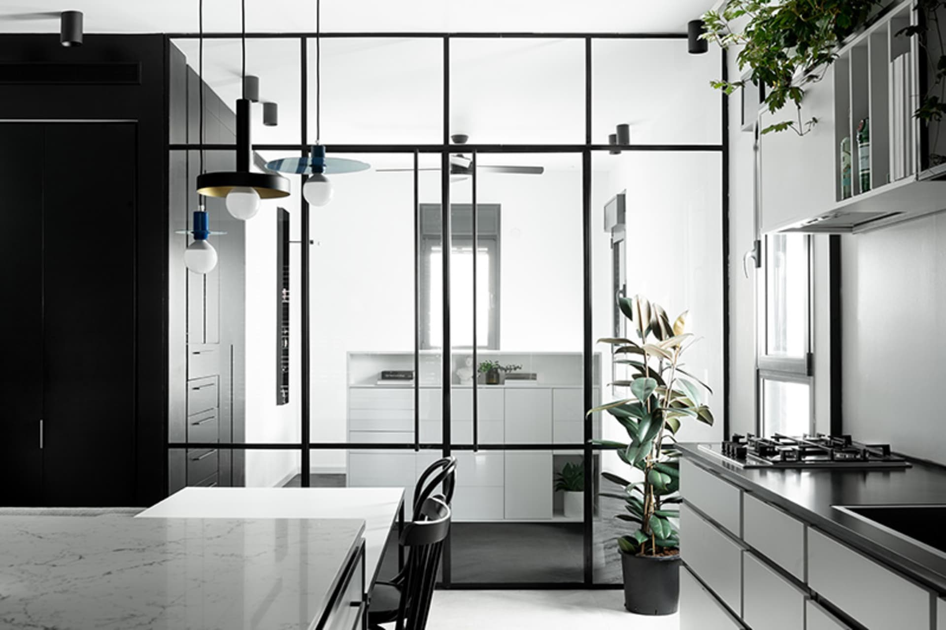 A modern kitchen features a marble countertop and black metal elements.
