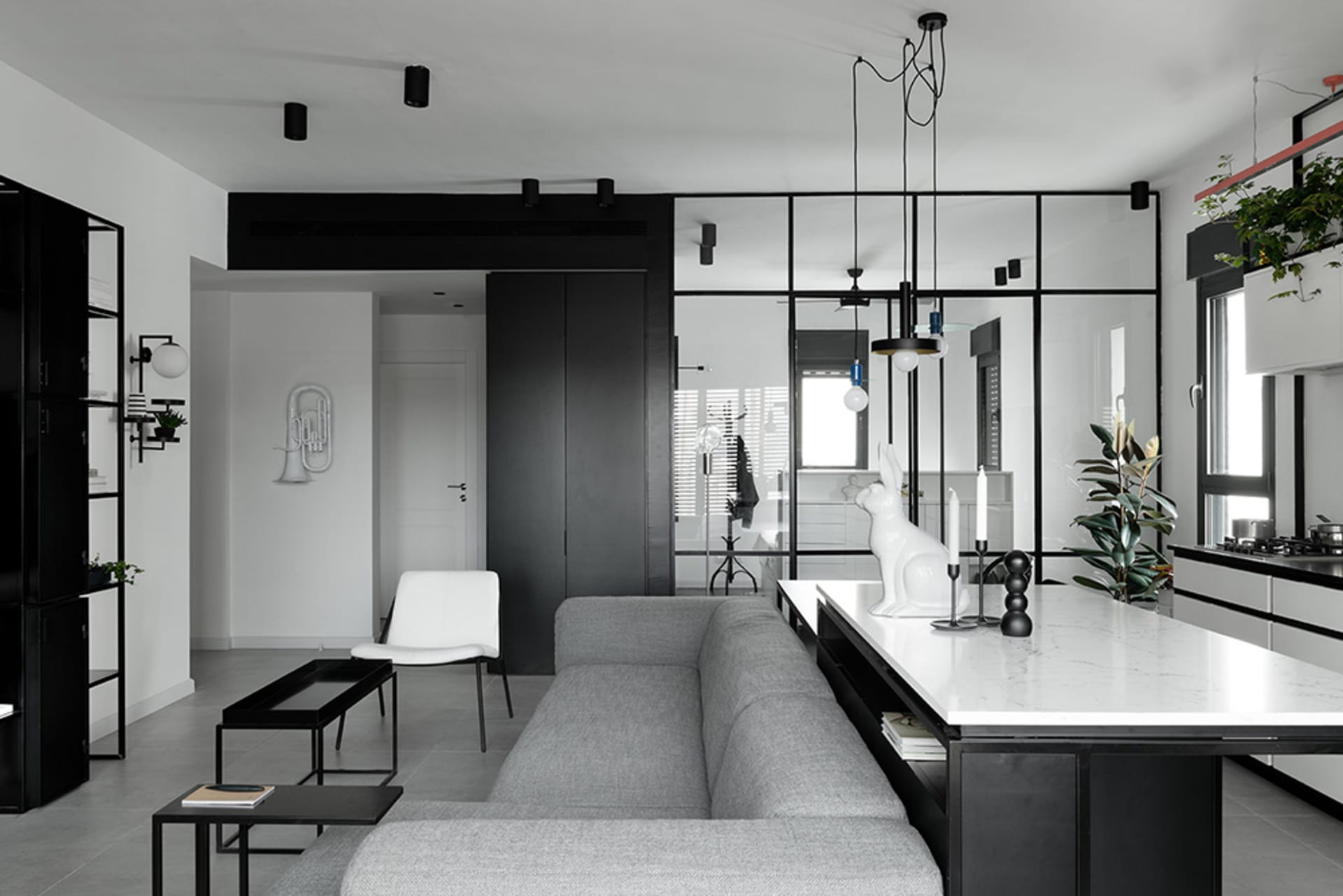 A modern minimalist living room with a grey sofa, black accents, and white marble countertops.