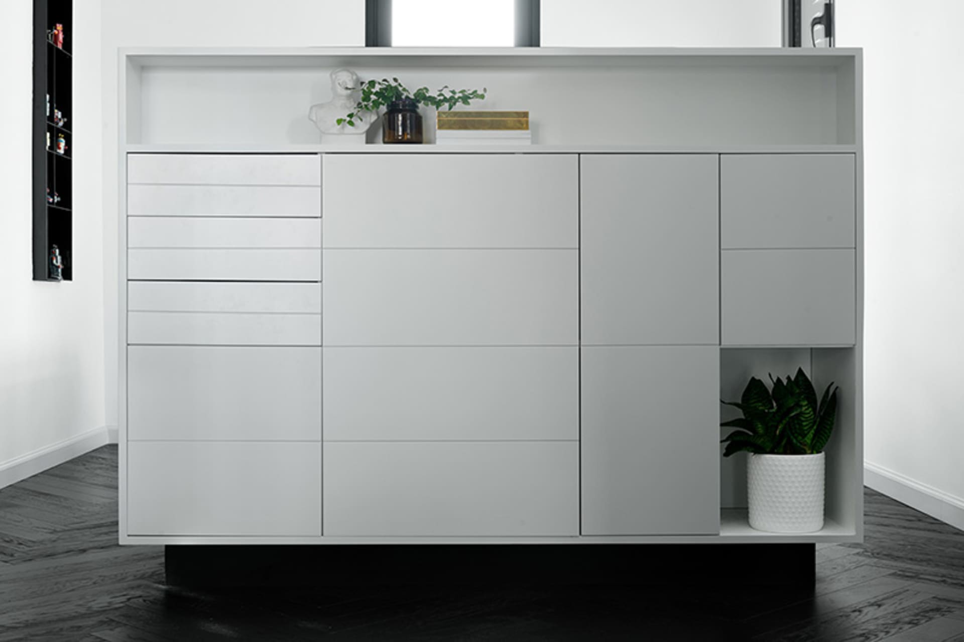 A modern, minimalist white concrete storage unit with three drawers, four doors, and open shelving.