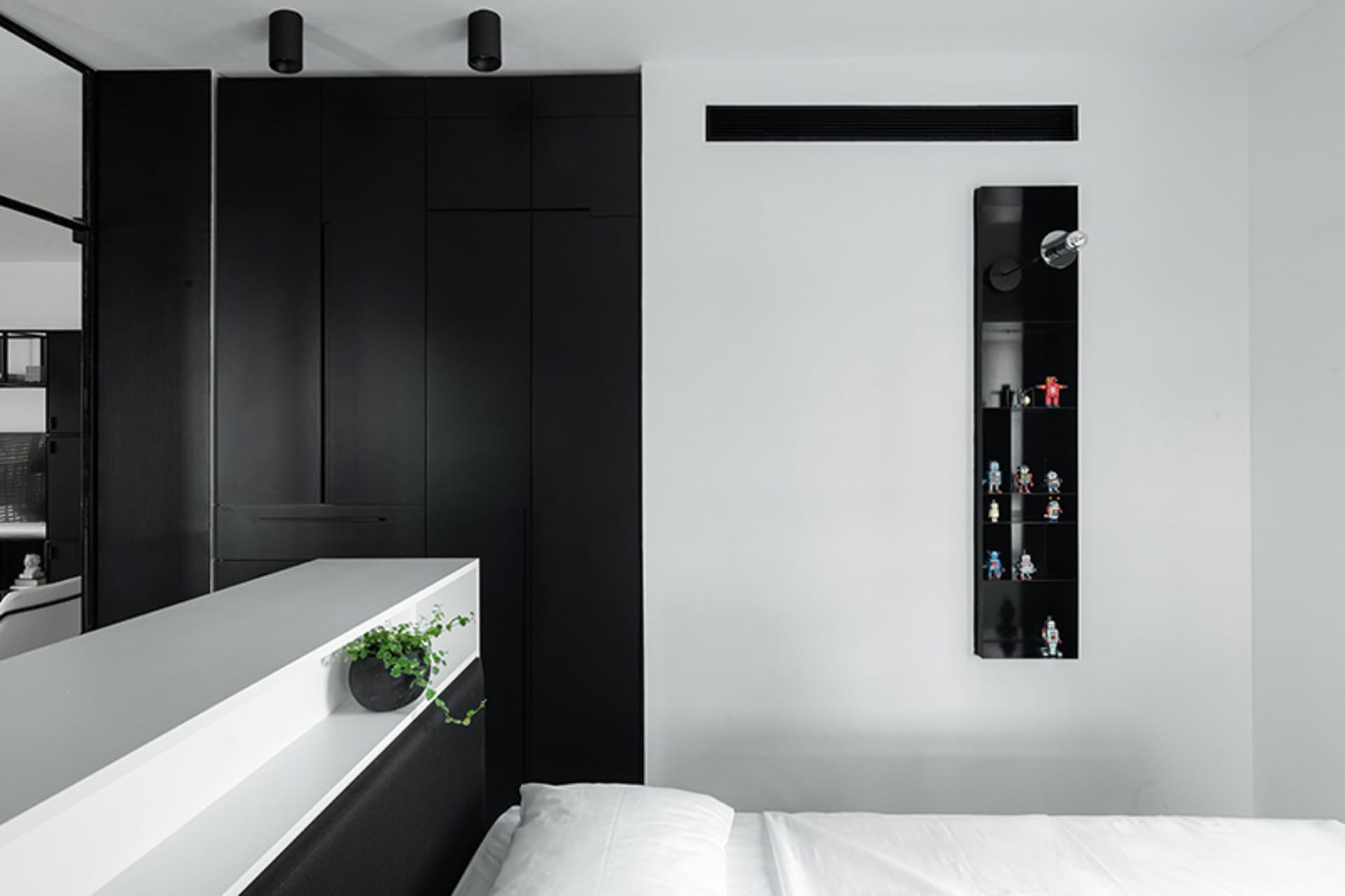 Modern minimalist bedroom featuring black and white color scheme and a bed with white bedding.