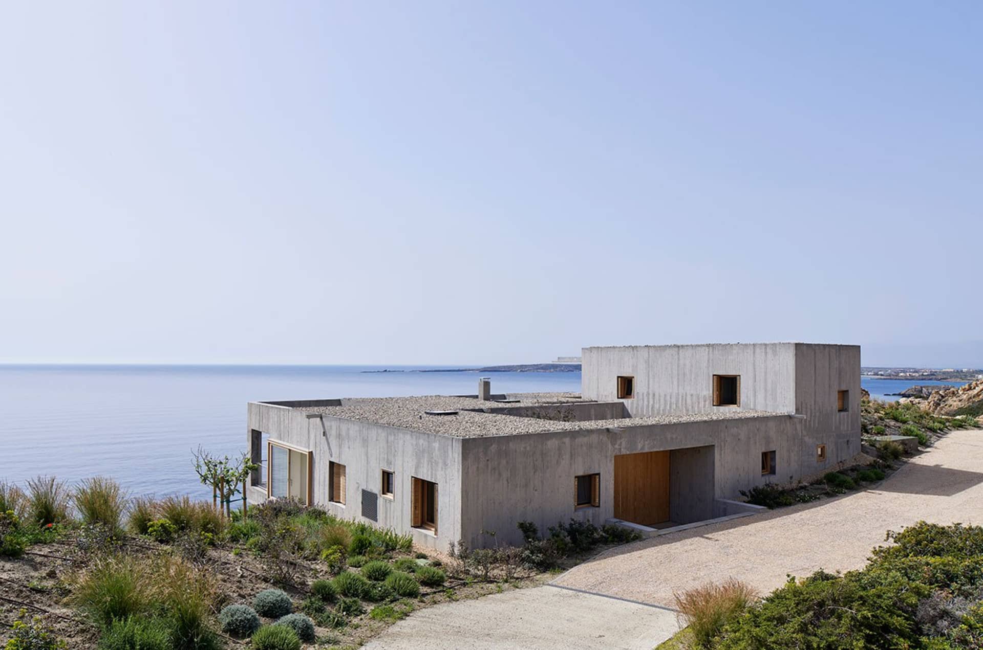 Modern, minimalist house with concrete facade overlooking the ocean.