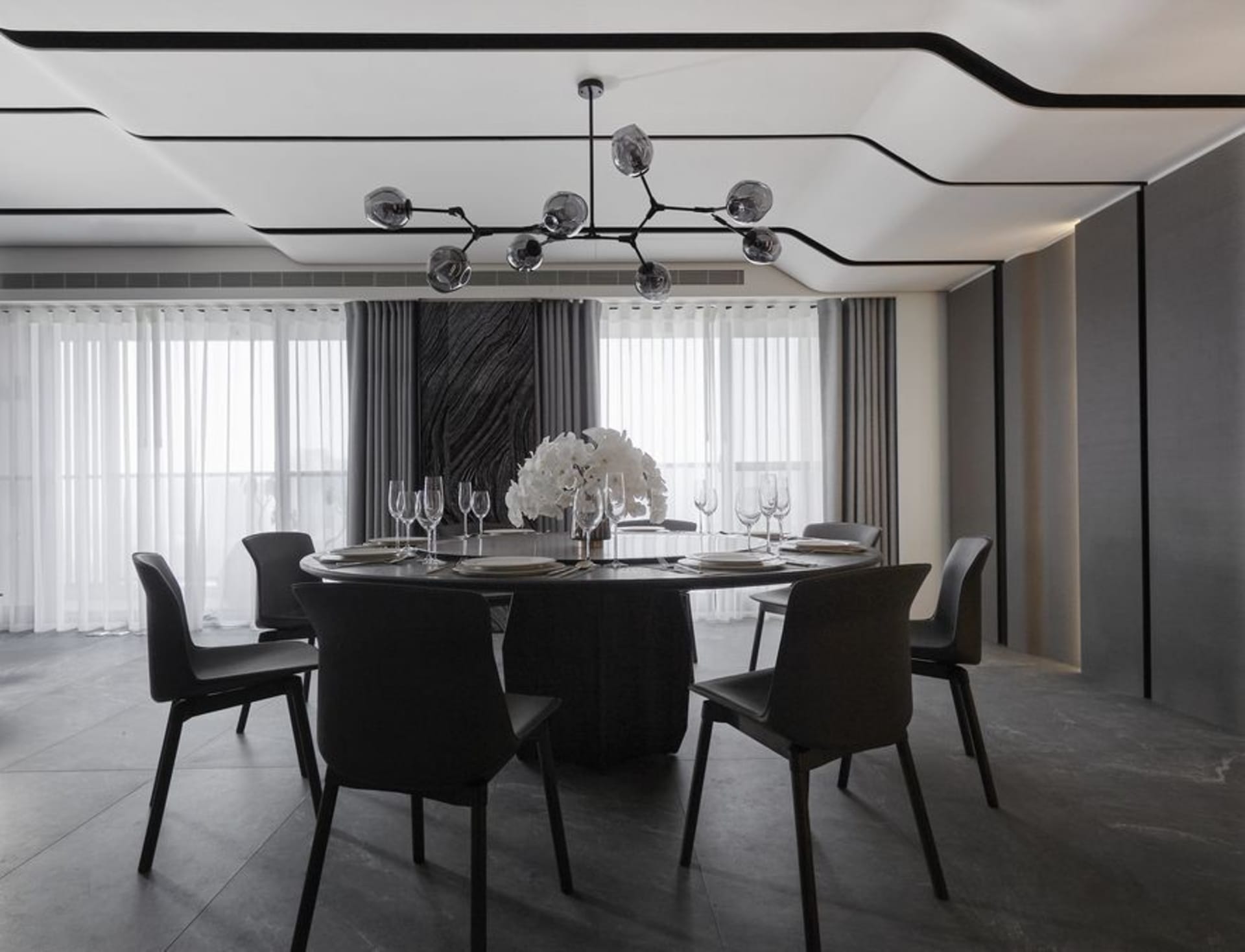 Modern dining room with glass table, metal chairs, and fabric seating