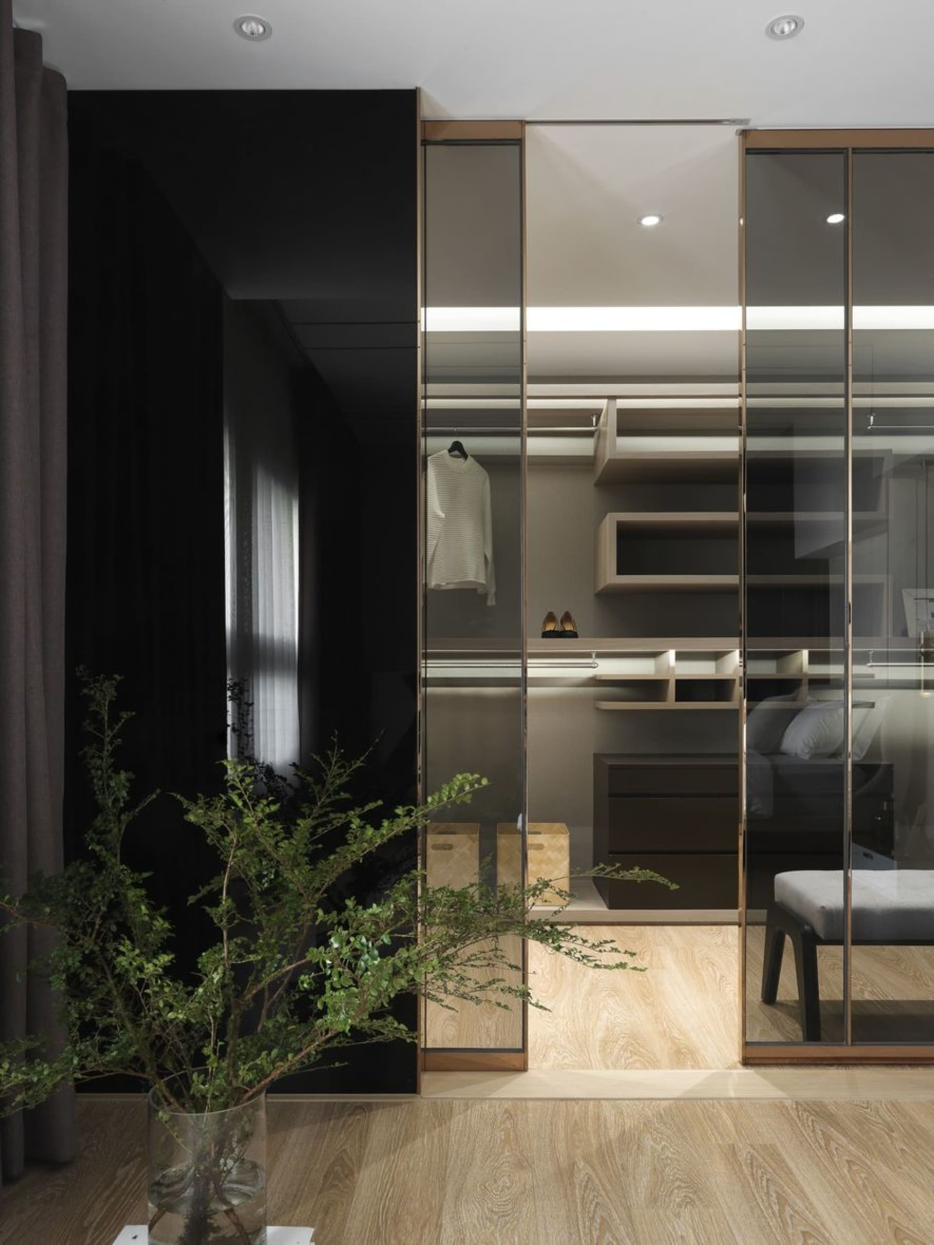 Modern minimalist closet with glass doors and wooden shelves.