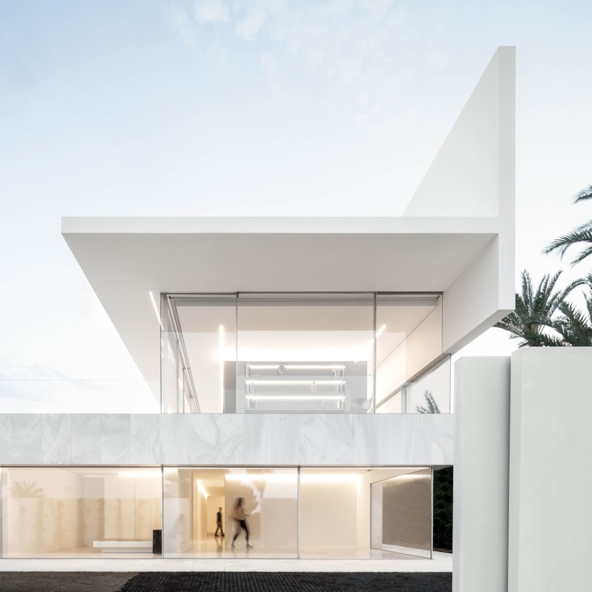 A modern house exterior with white marble materials and large glass windows.