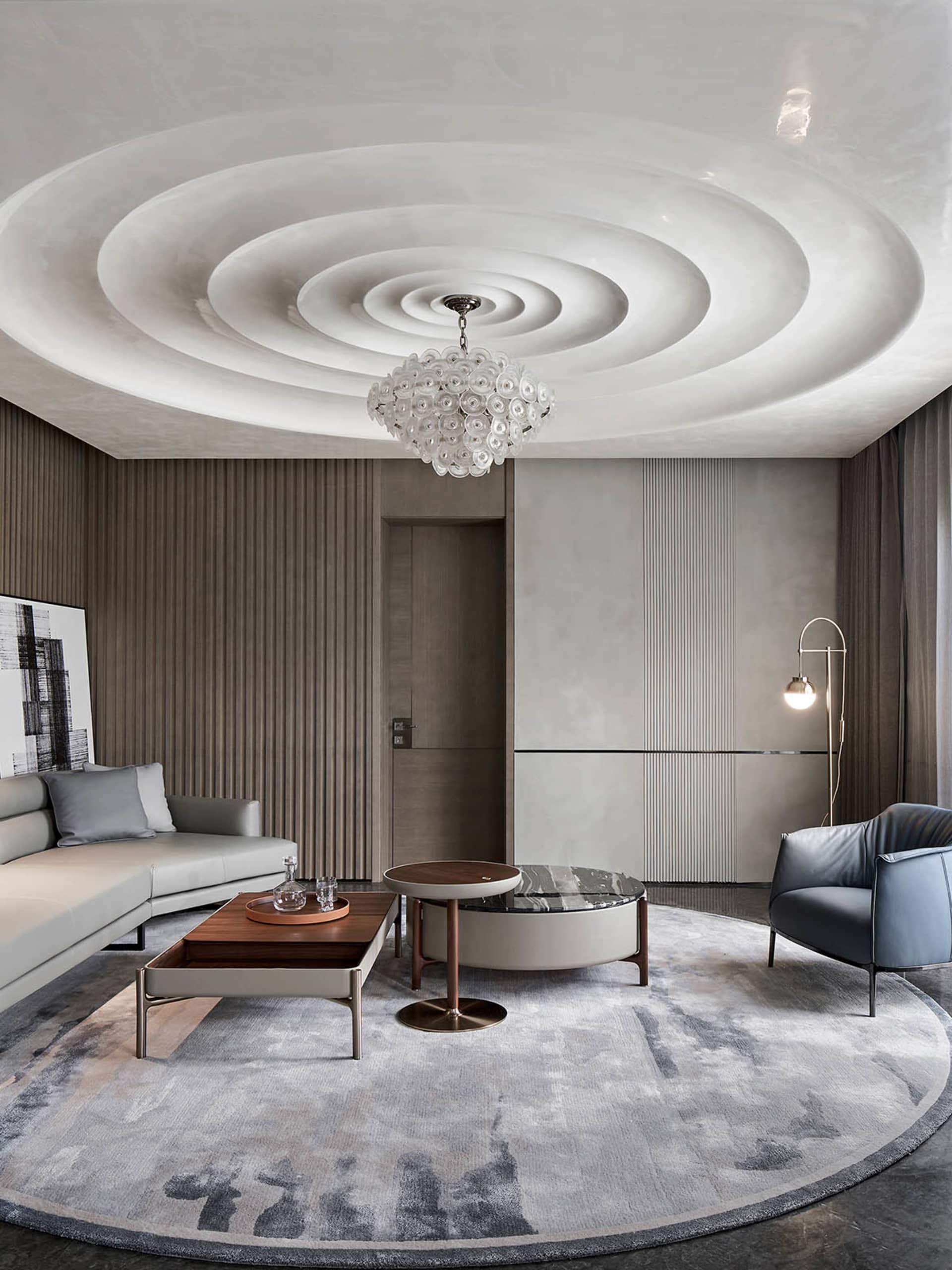 Modern living room featuring a white round ceiling with concentric circles, a large circular coffee table, and a long gray so
