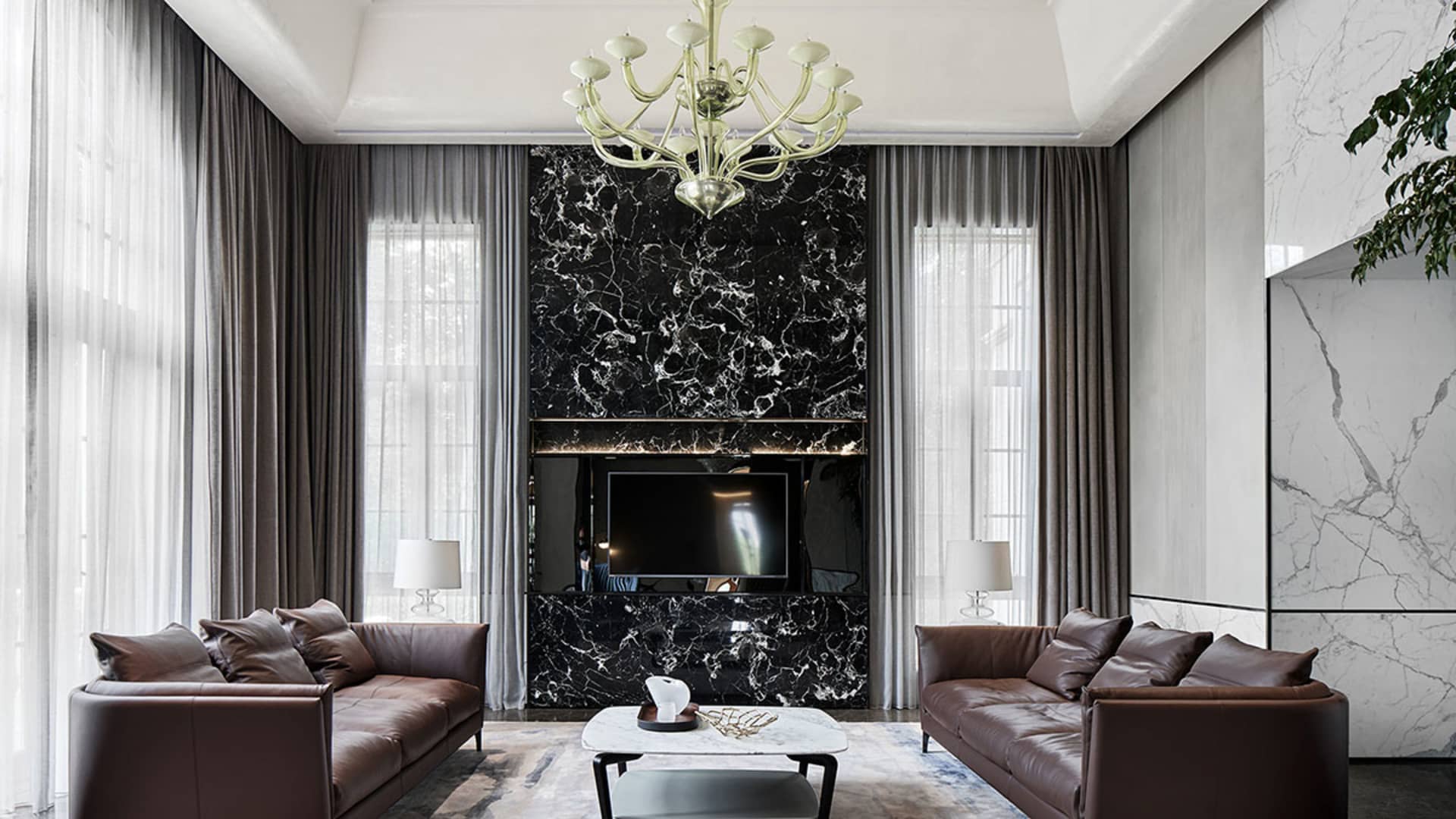 Modern living room featuring a black marble accent wall, brown leather sofas, and a marble coffee table.
