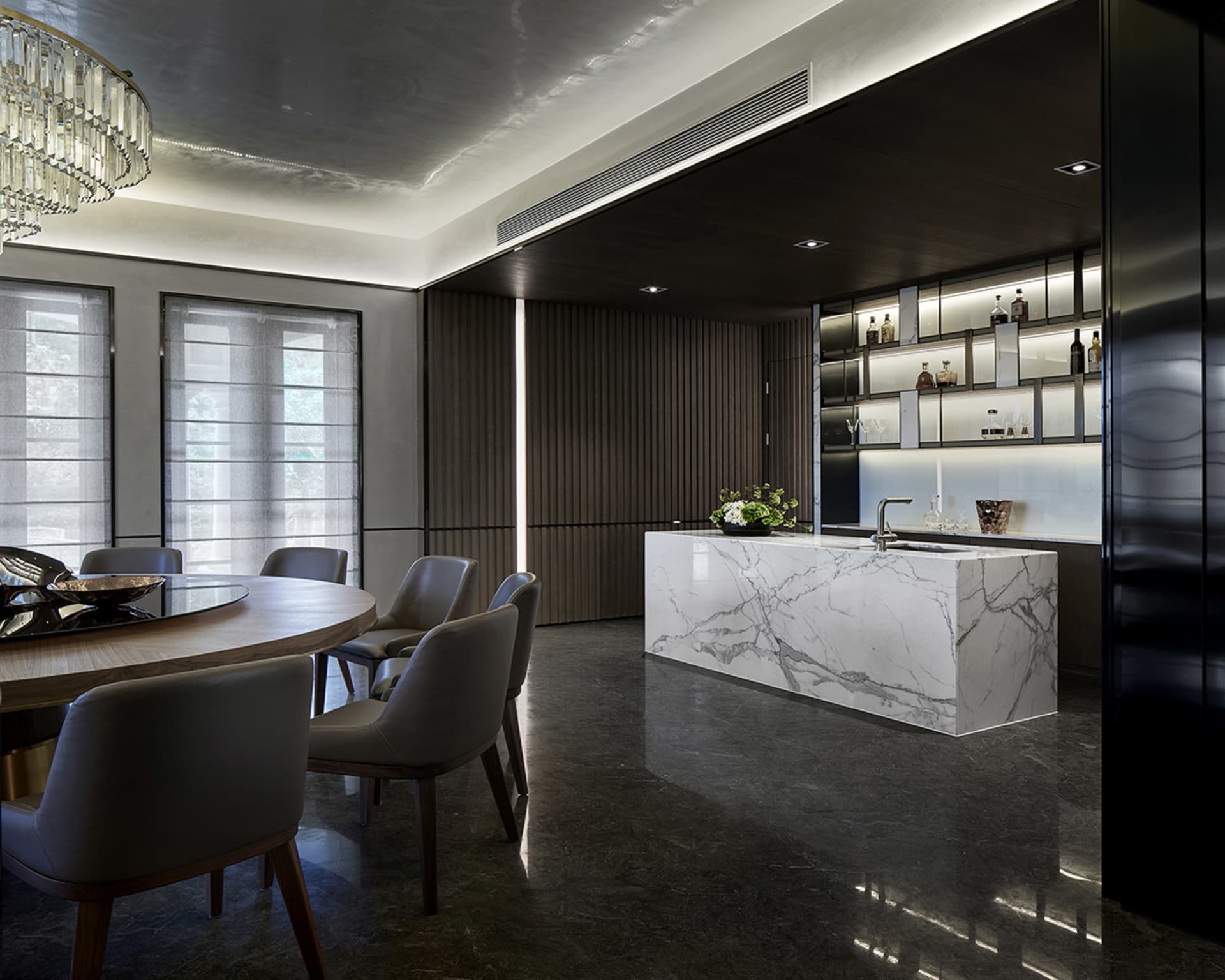 Modern residential kitchen featuring a marble countertop and a round dining table with gray chairs.