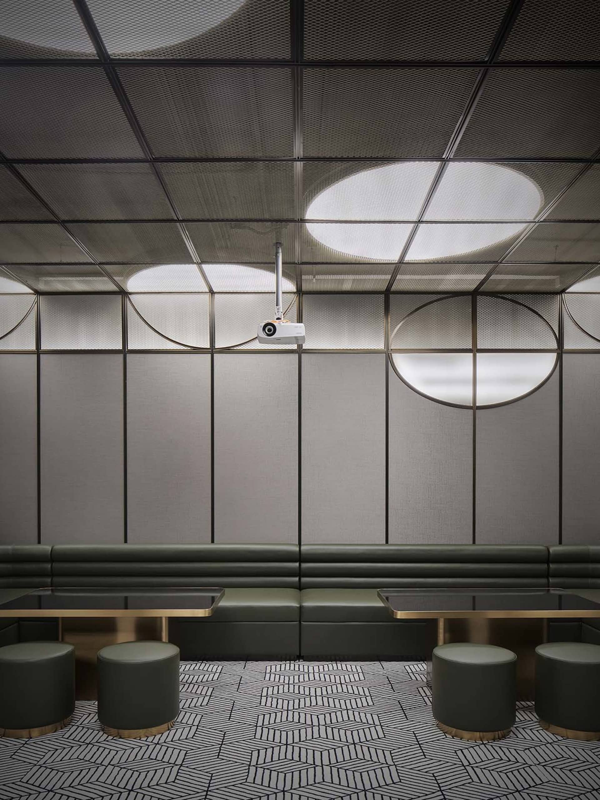 Modern industrial restaurant dining room with metallic textured panels and green leather seating.