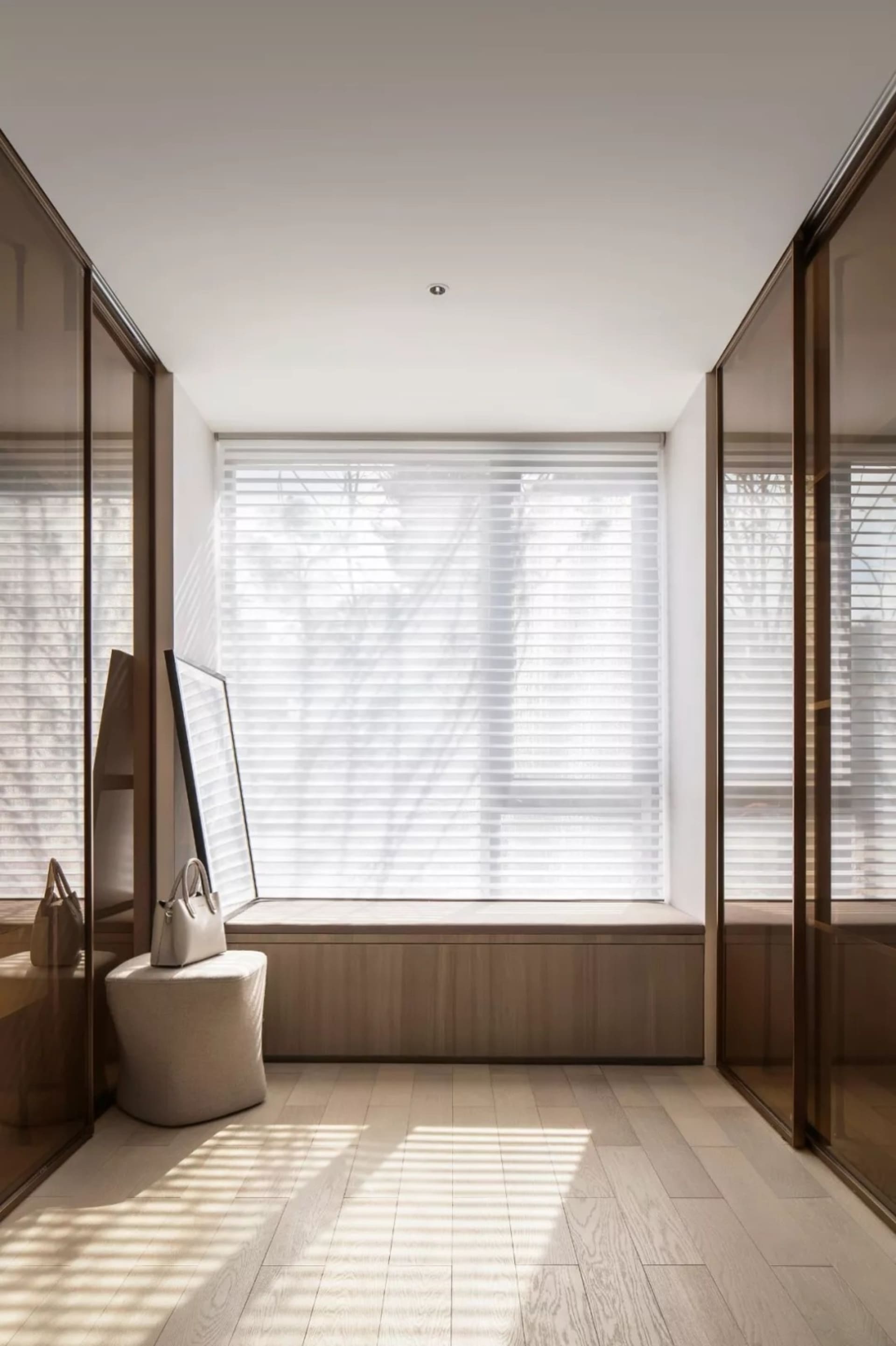 Modern, minimalist living room with a window seat and wood flooring.