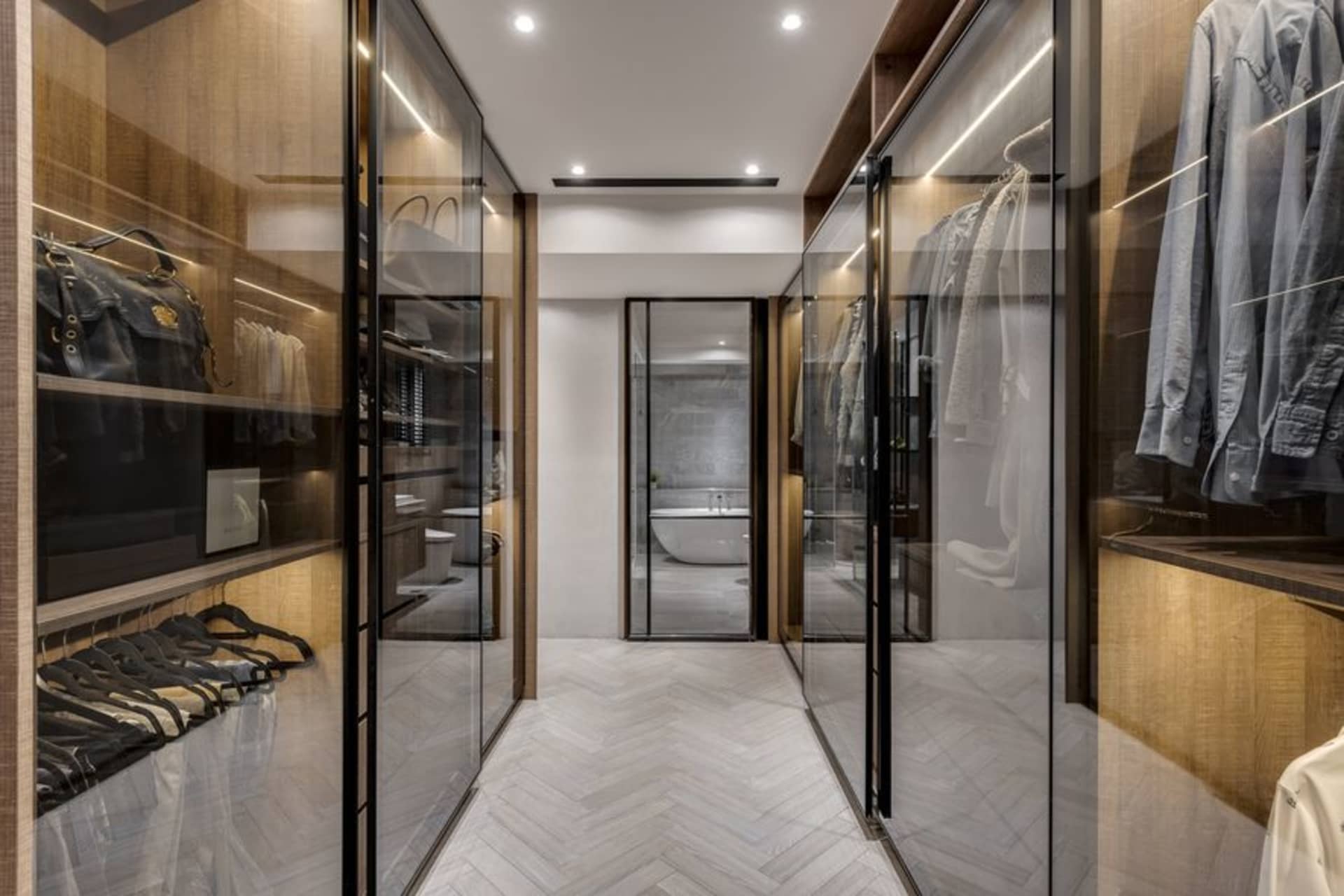 Modern closet and bathroom with wooden, glass, and marble features.