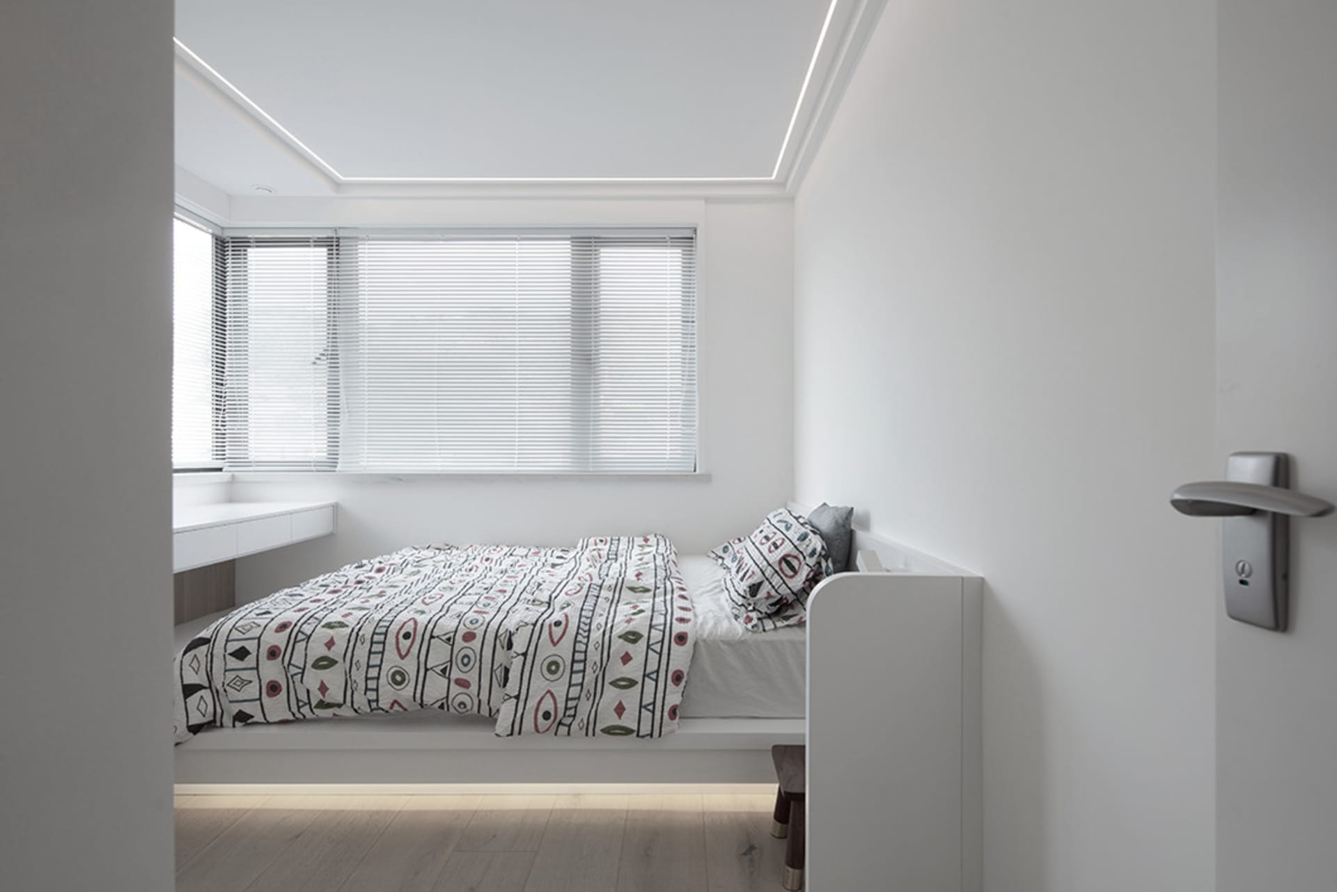 A modern bedroom with a bed, window, and wooden floor.