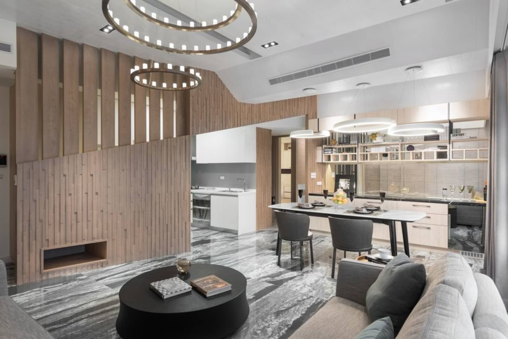 A modern living, dining, and kitchen space featuring wooden paneling and a marble countertop.