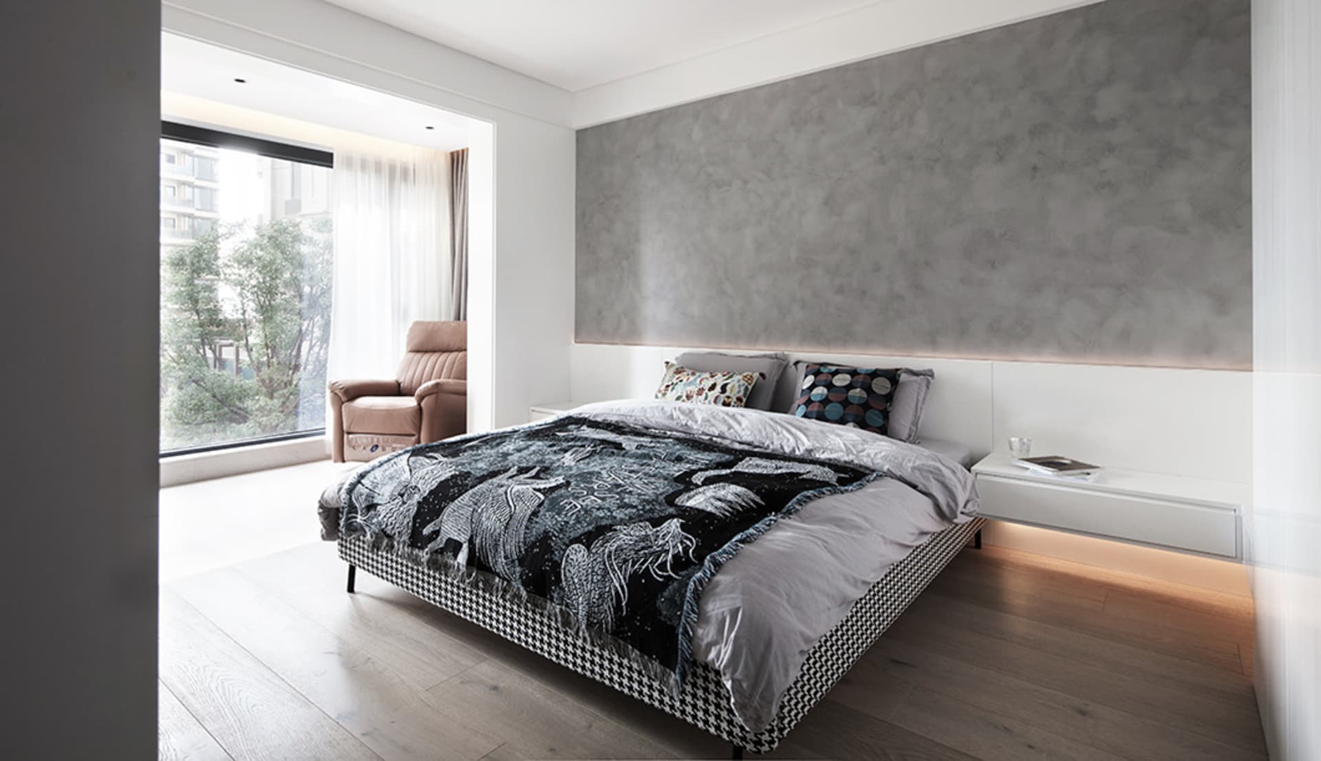 A modern minimalist bedroom featuring a concrete accent wall and a bed with a black and white checkered quilt, set against a