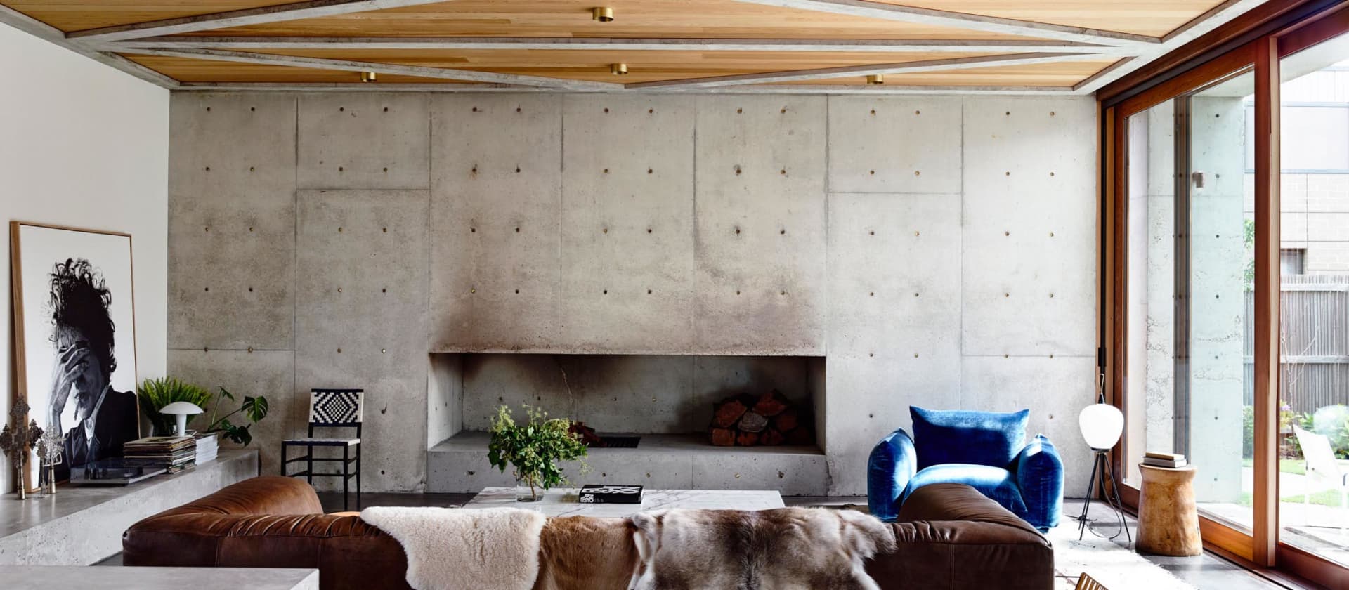 Industrial-style interior space with concrete walls, brown leather sofas, and blue armchair.