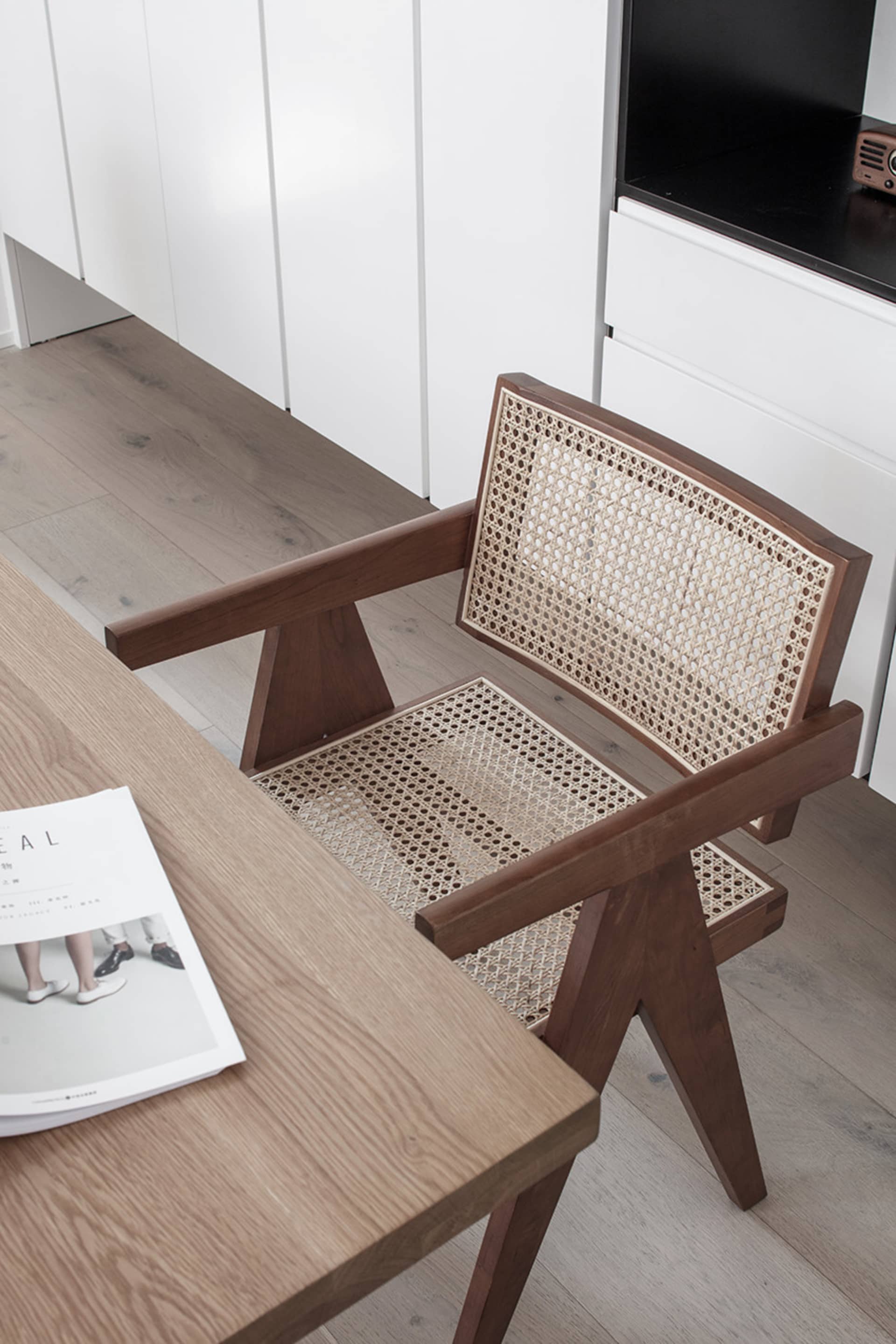 A minimalist office setting featuring a wooden and woven cane chair.