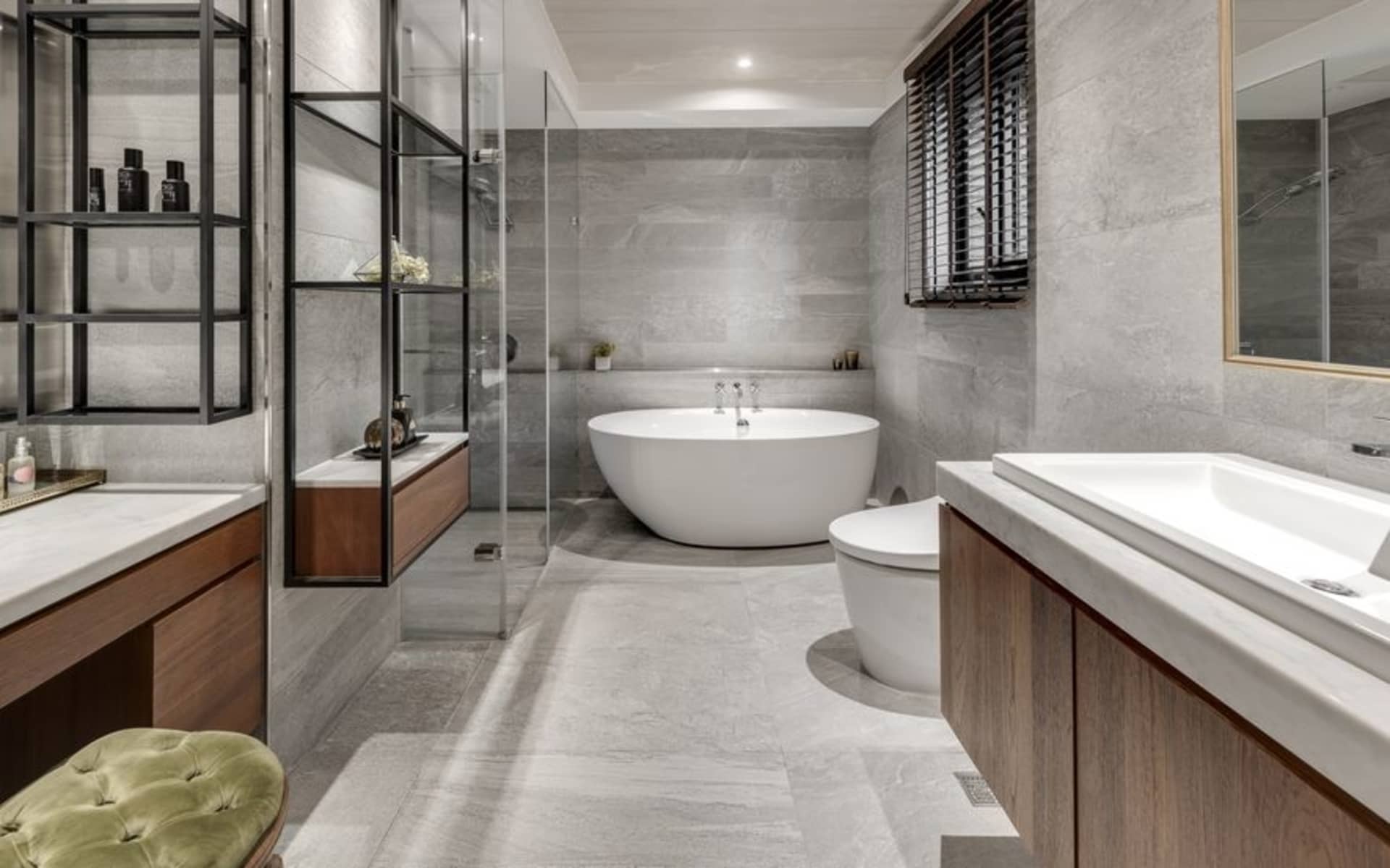 A modern bathroom interior with a concrete surface, featuring a freestanding bathtub, walk-in shower, and wooden vanities.
