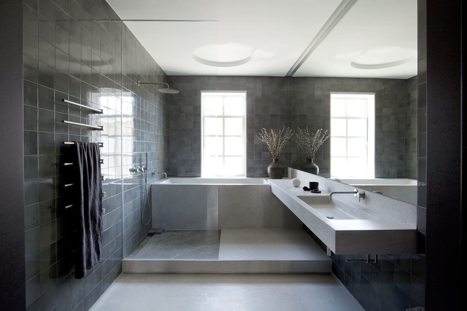 A minimalist bathroom featuring grey tiles, concrete elements, and a contemporary design.