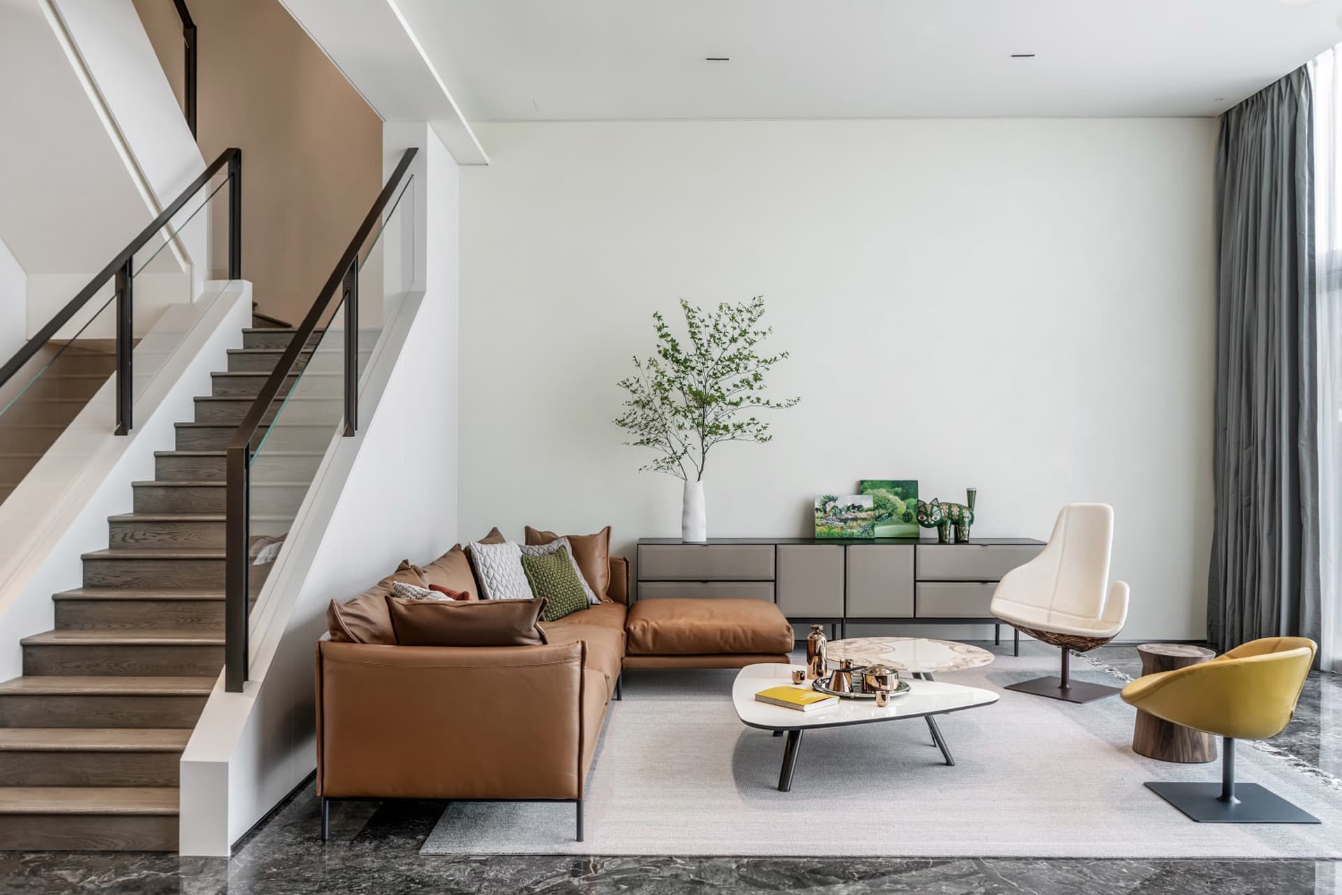 A modern living room with a brown leather couch, white coffee table, and minimalist decor.
