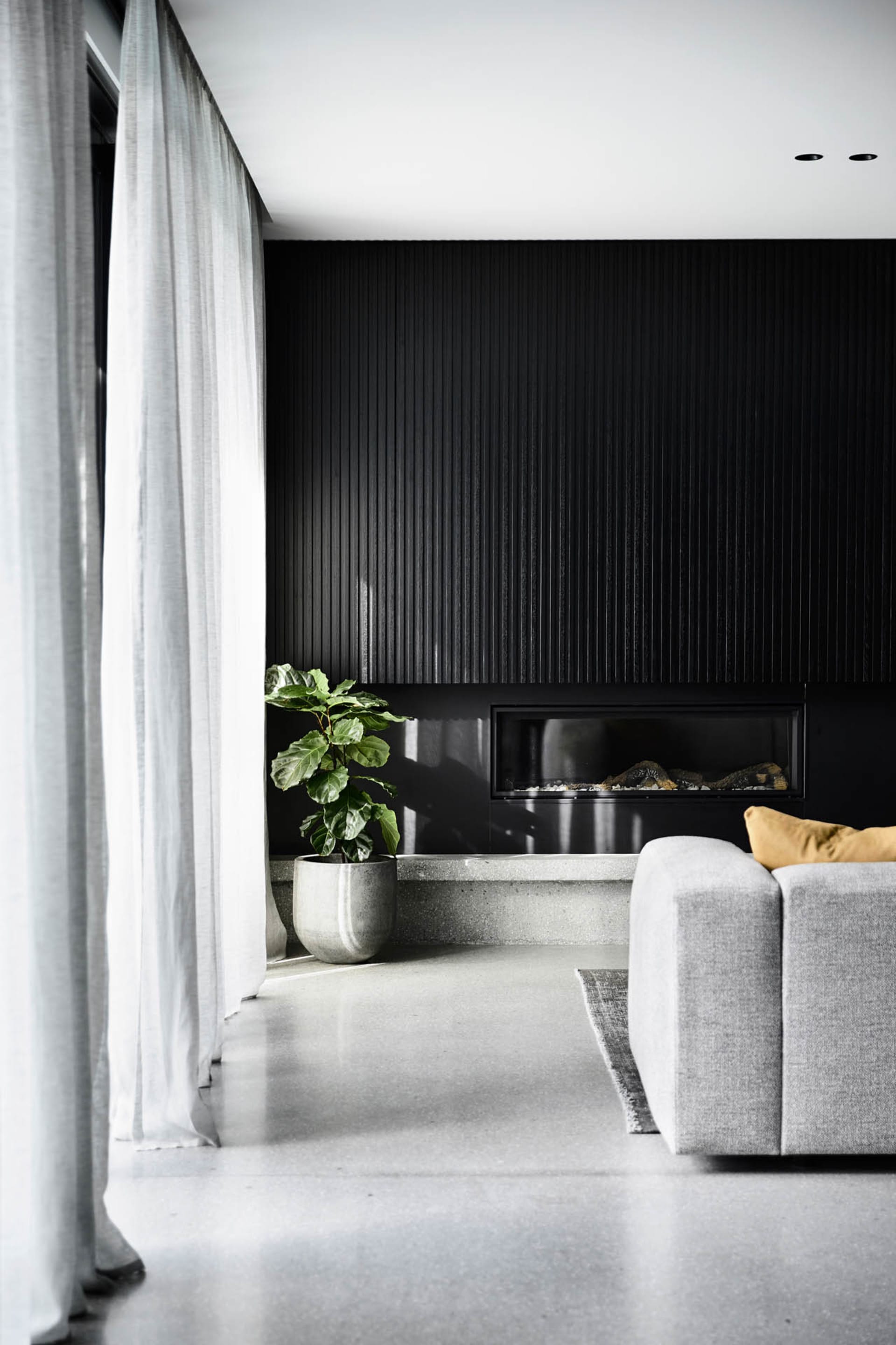 A modern living room with a concrete floor, minimalist design, and a fireplace.