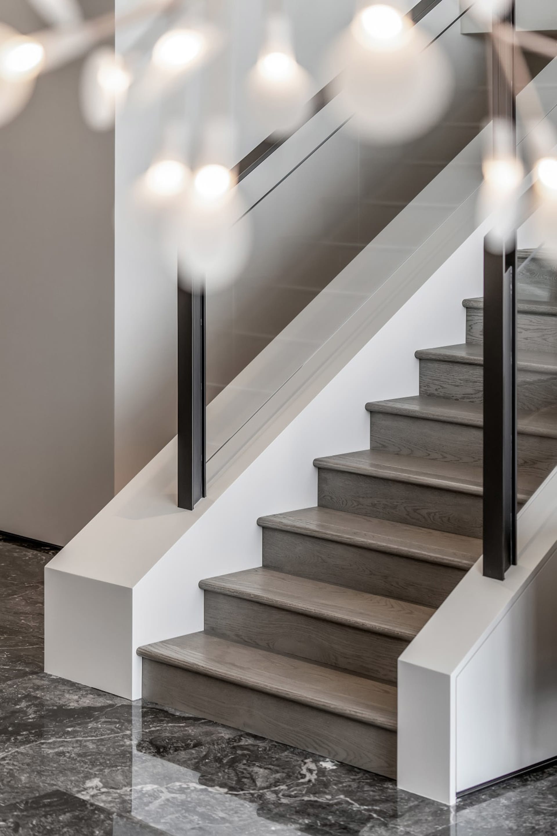 A modern staircase with wooden steps, glass railings, and a concrete base.