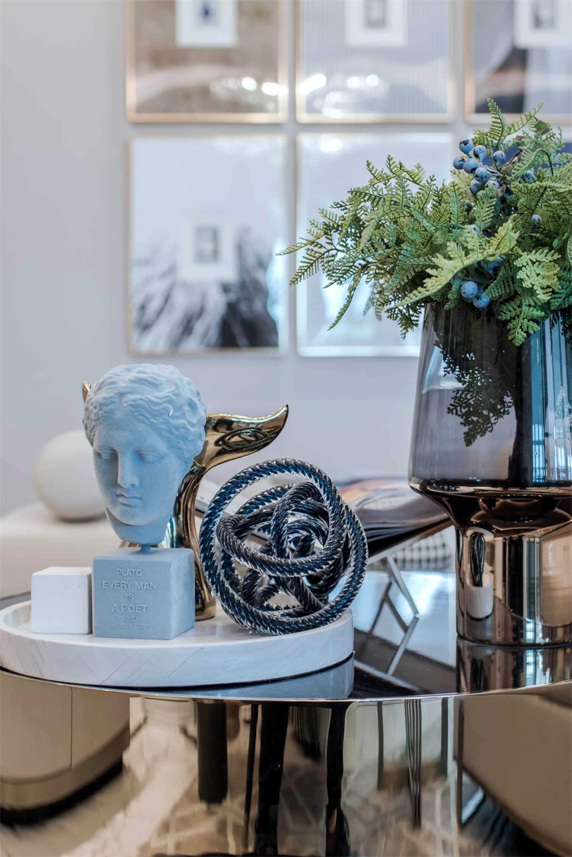 A modern interior space featuring metallic elements, glass vases, and wooden sculptures.