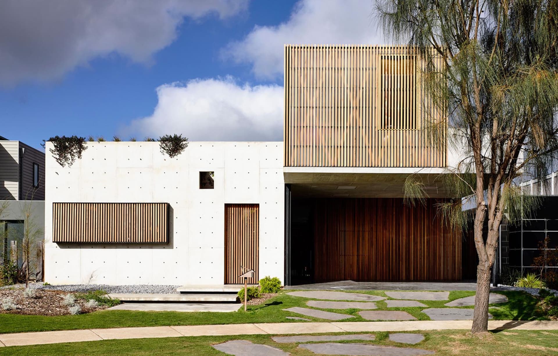 Modern residential home with concrete exterior and wooden accents on the upper level.