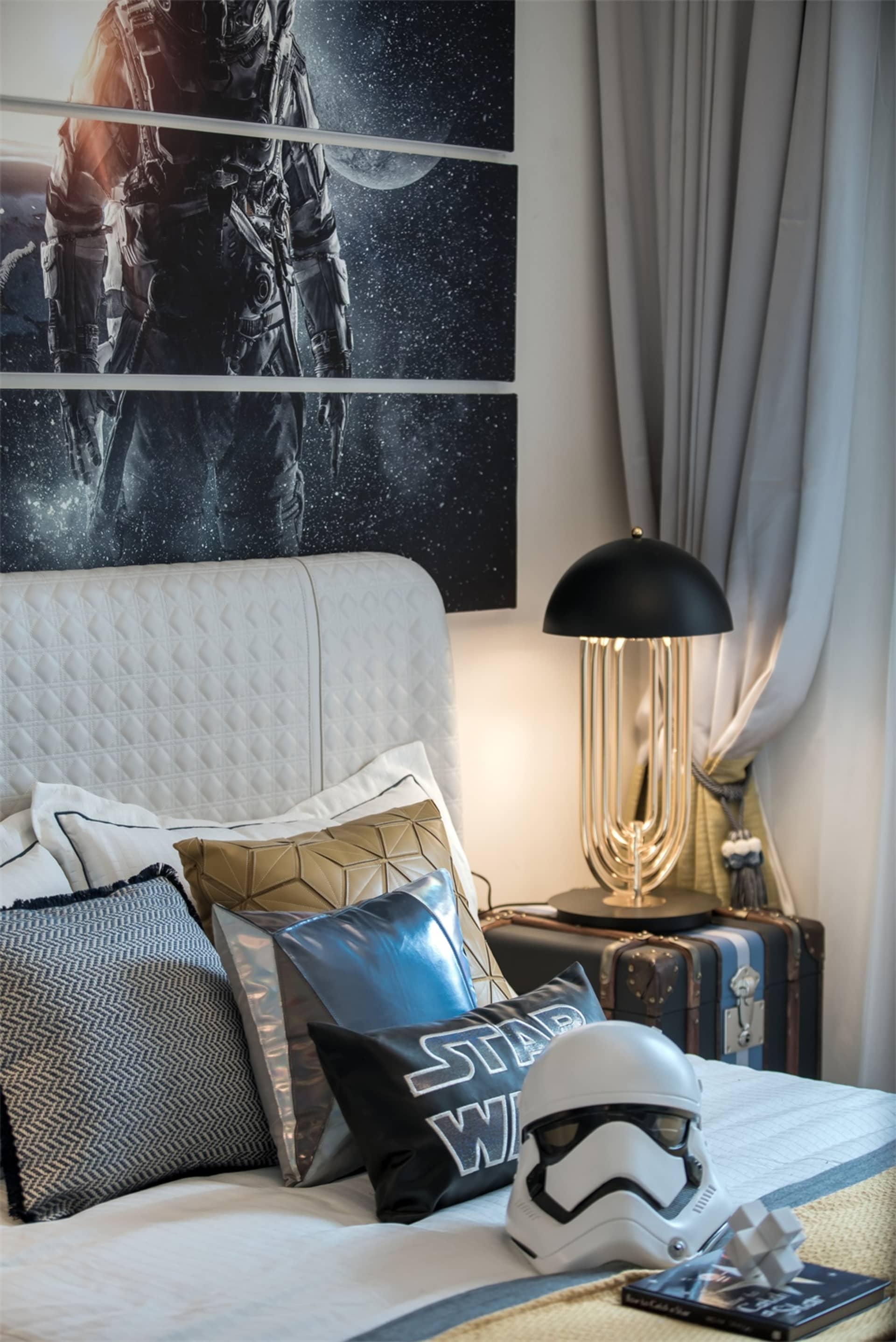 Bedroom featuring a white upholstered headboard with various pillows and a stormtrooper helmet on the bed.
