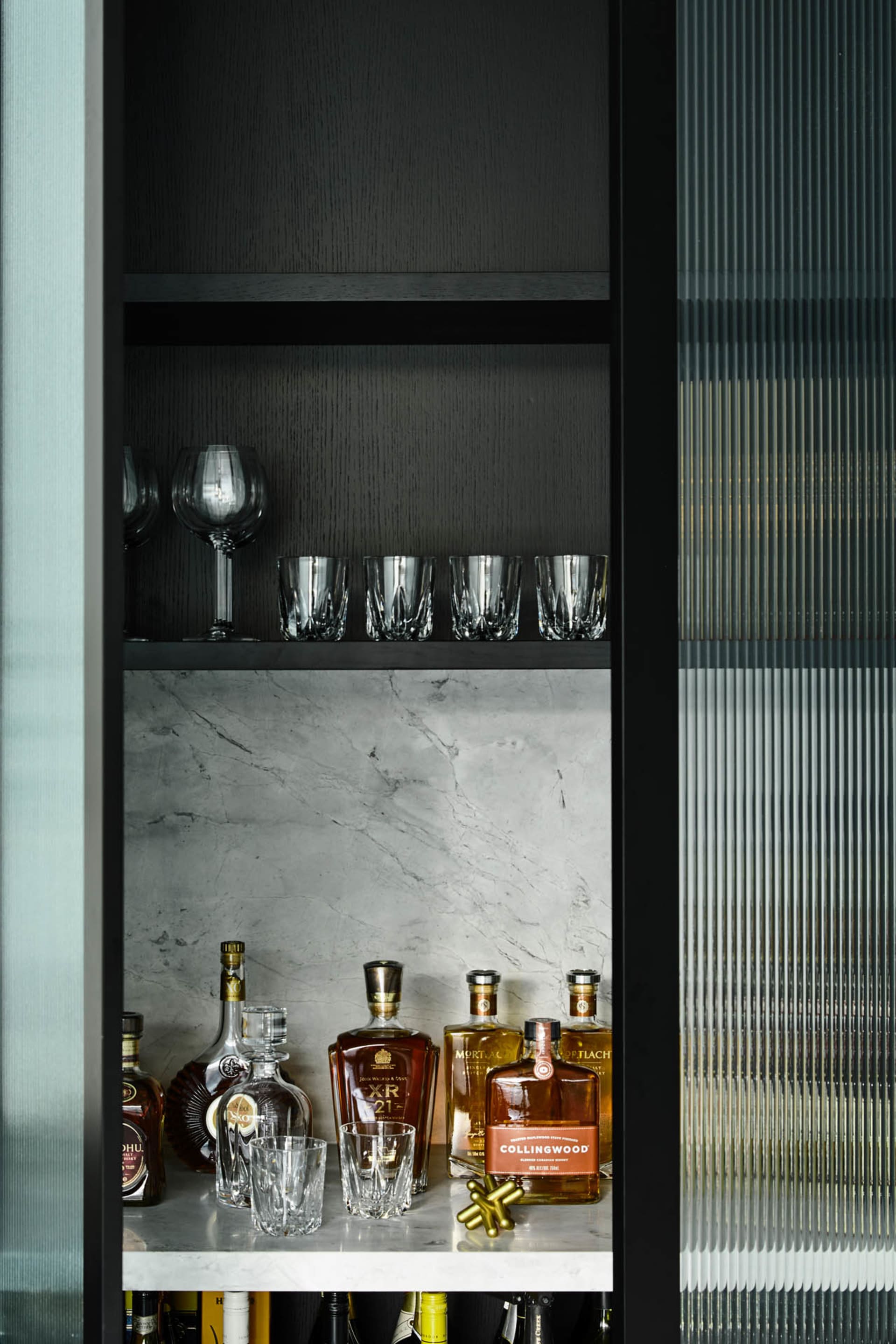 Modern bar shelf featuring marble and glass with various bottles of alcohol